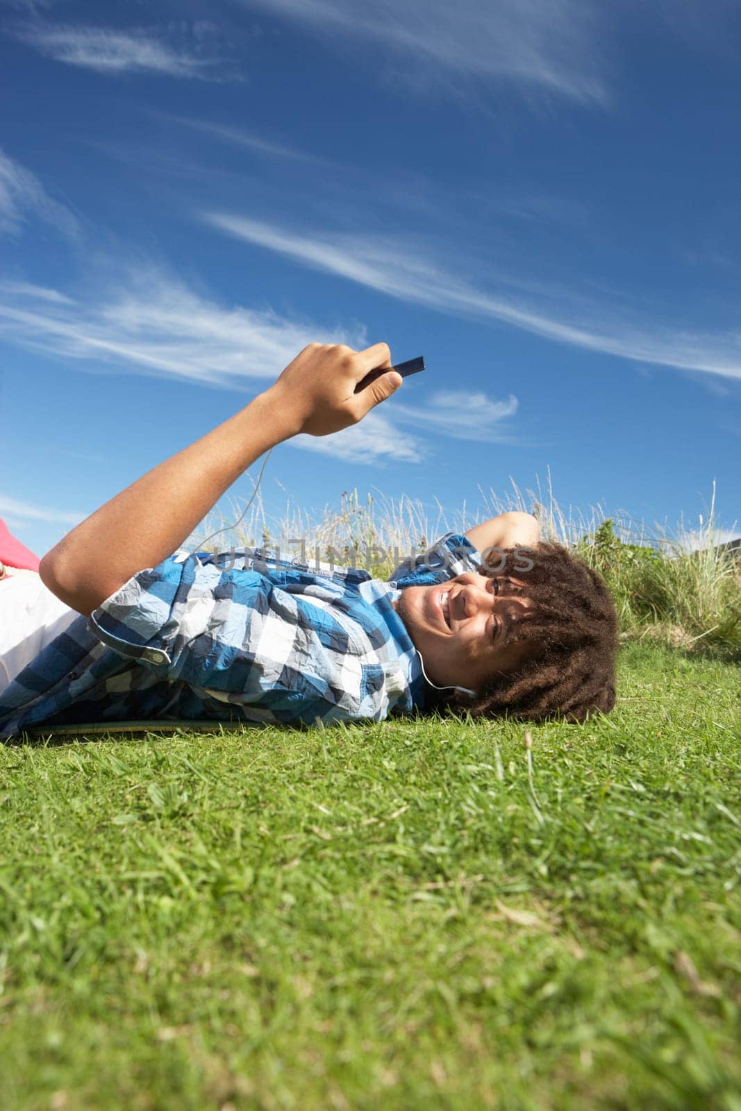 Teenage boy lying on grass with phone