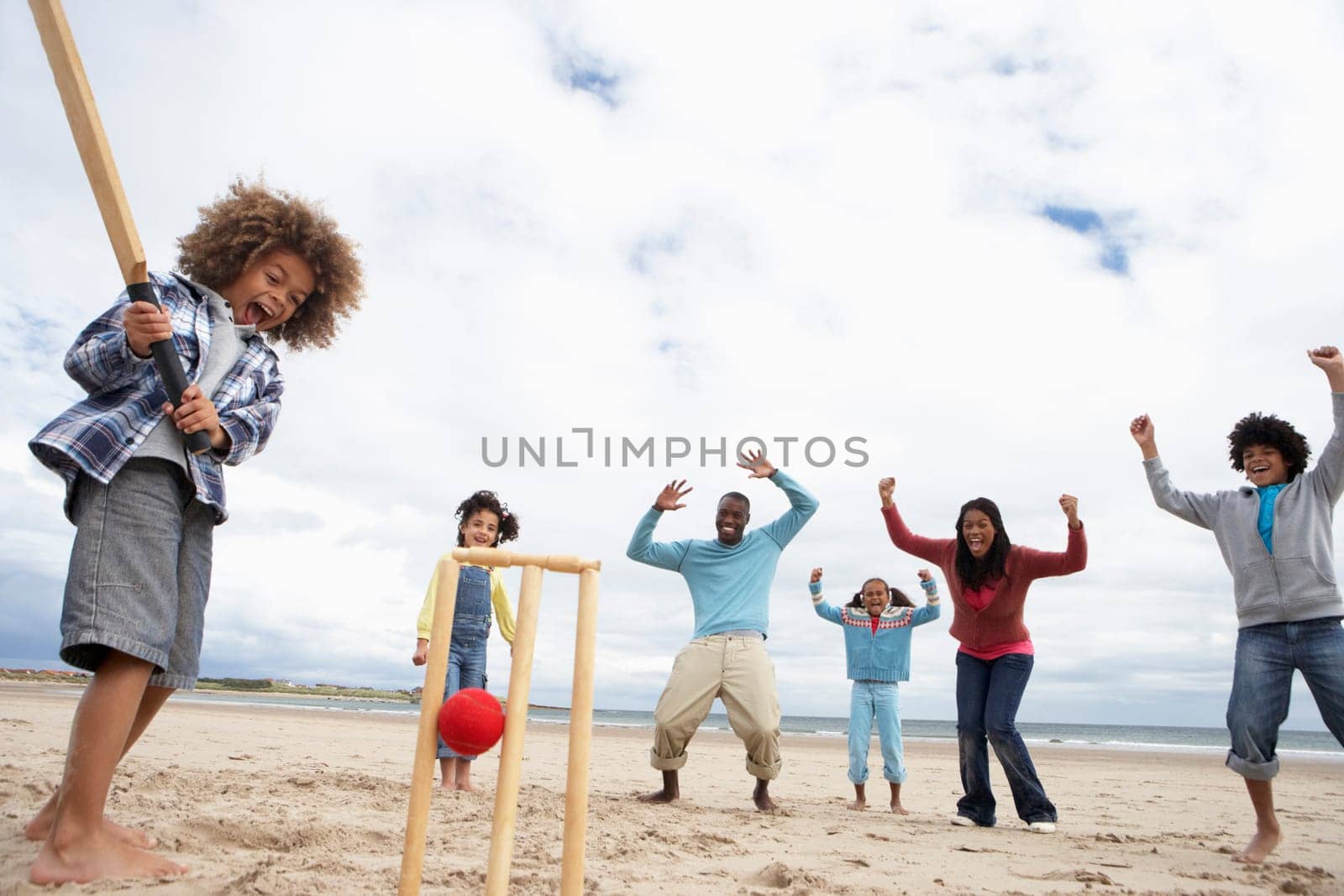 Family playing cricket on beach