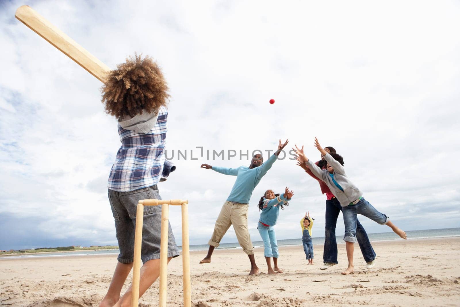 Family playing cricket on beach