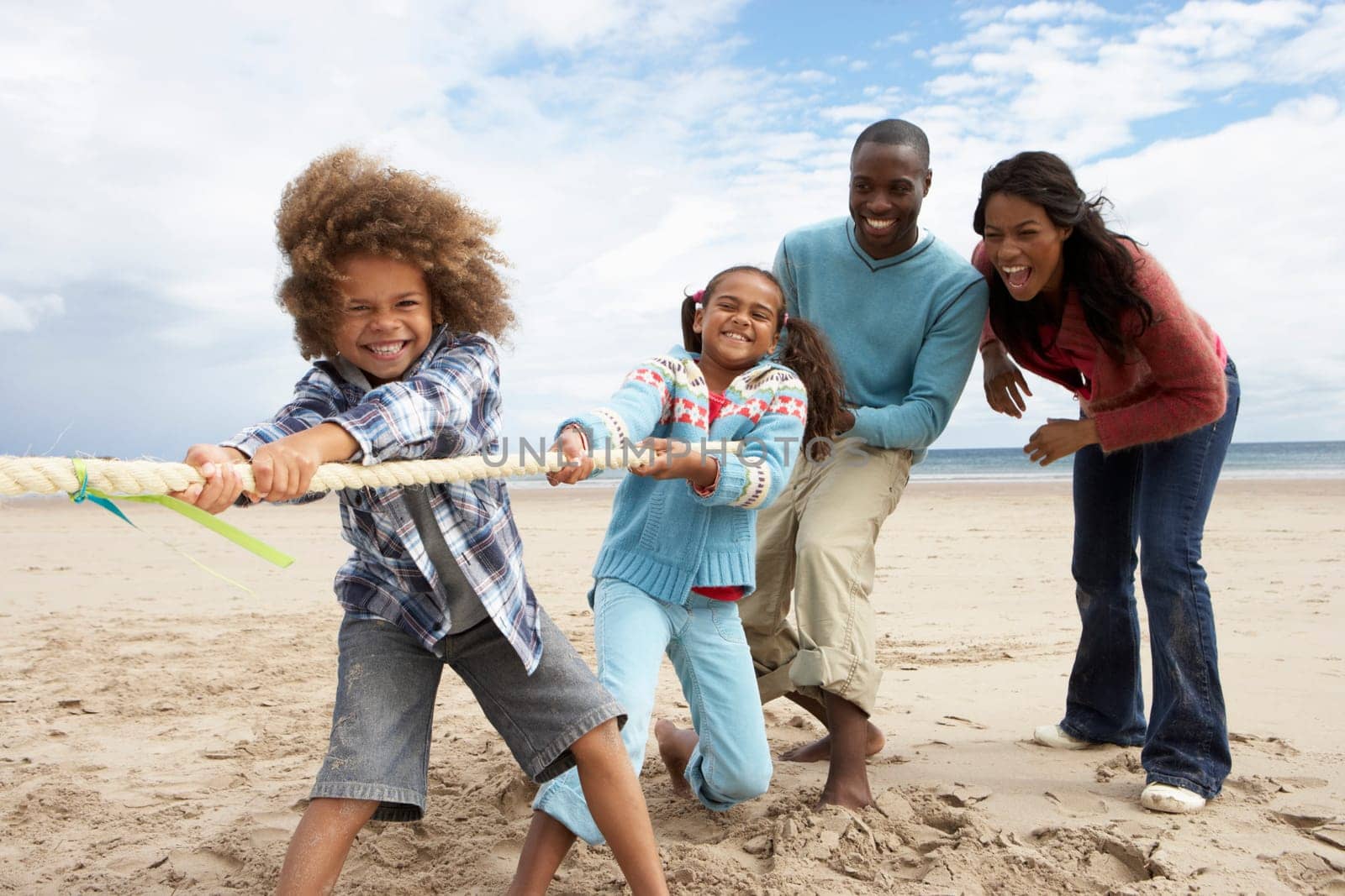 Family playing tug of war on beach