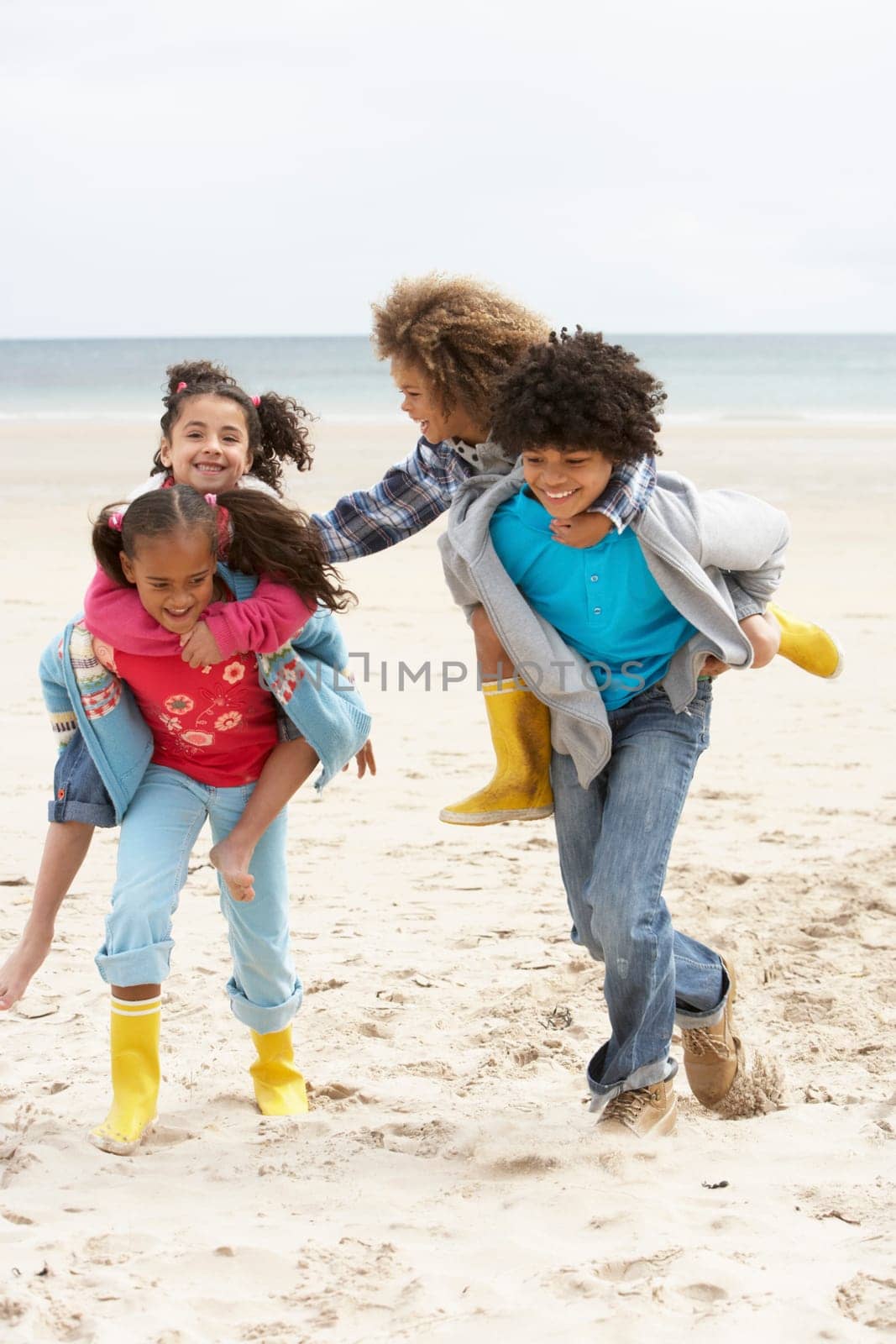Happy children playing piggyback on beach