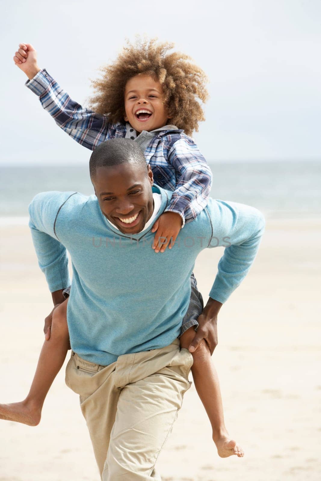 Father and son playing piggyback on beach