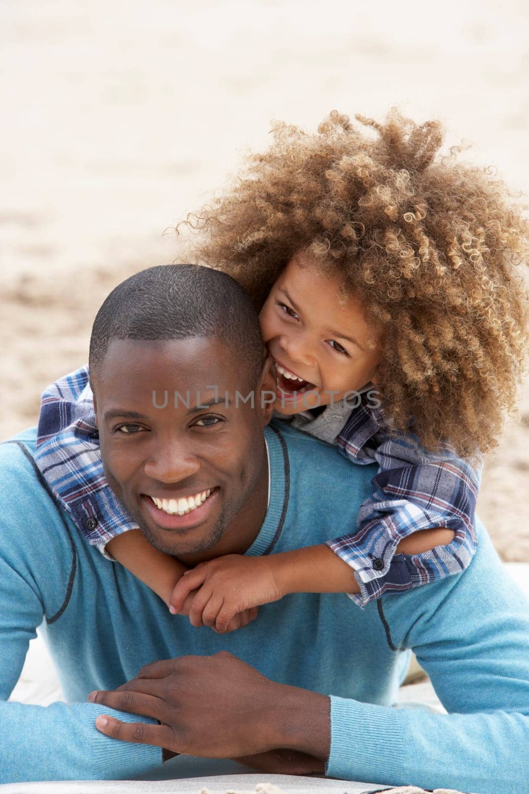 Father and son playing piggyback on beach