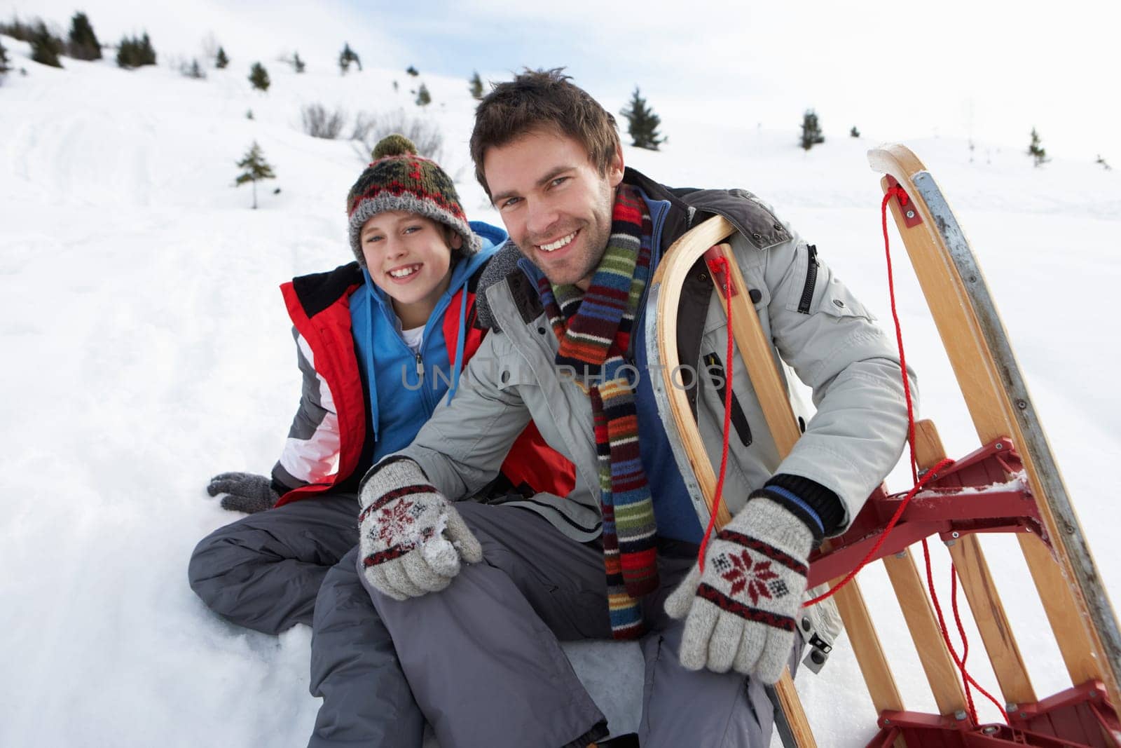 Young Father And Son In Snow With Sled