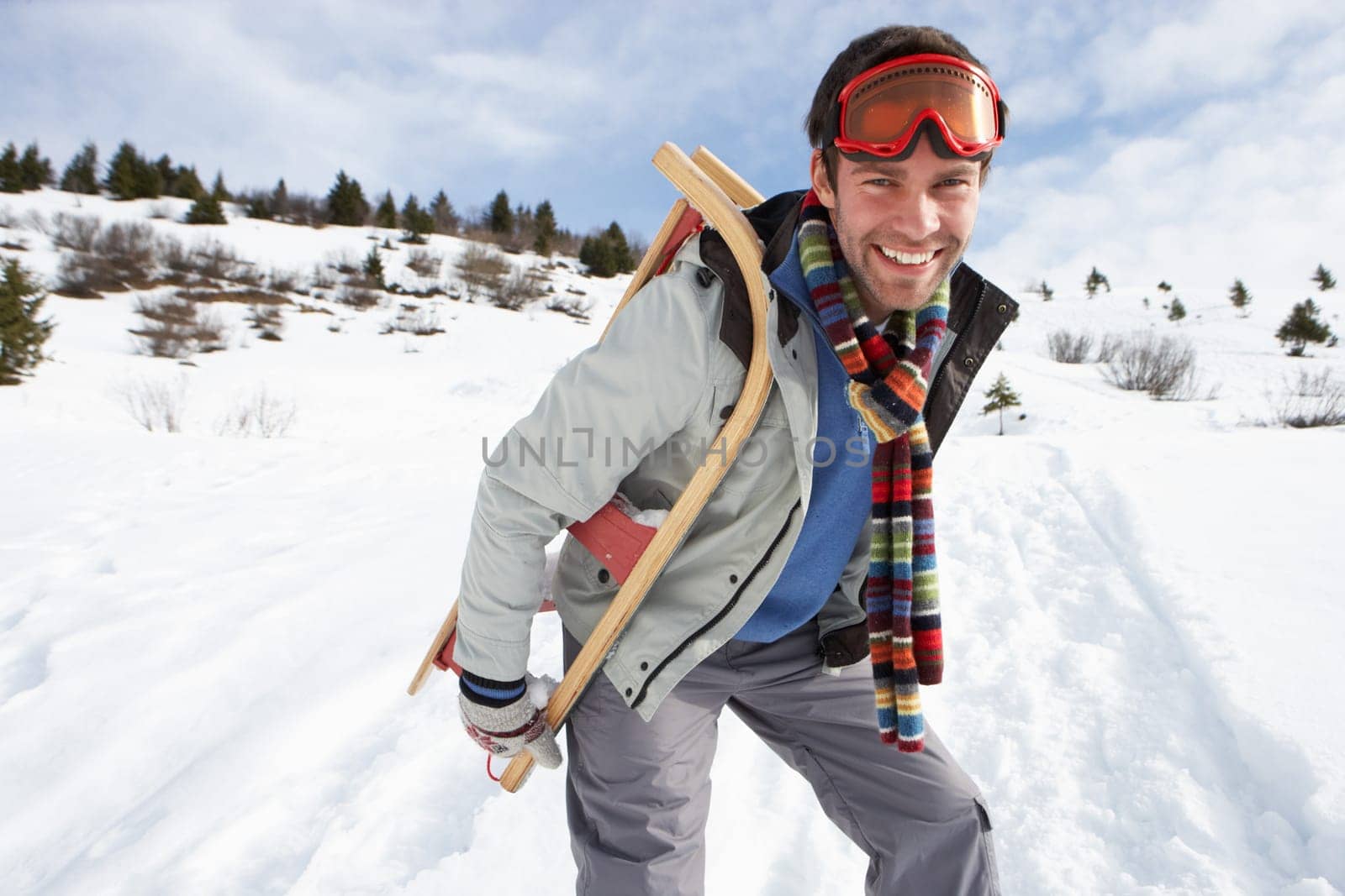 Young Man Carrying Sled In Alpine Landscape