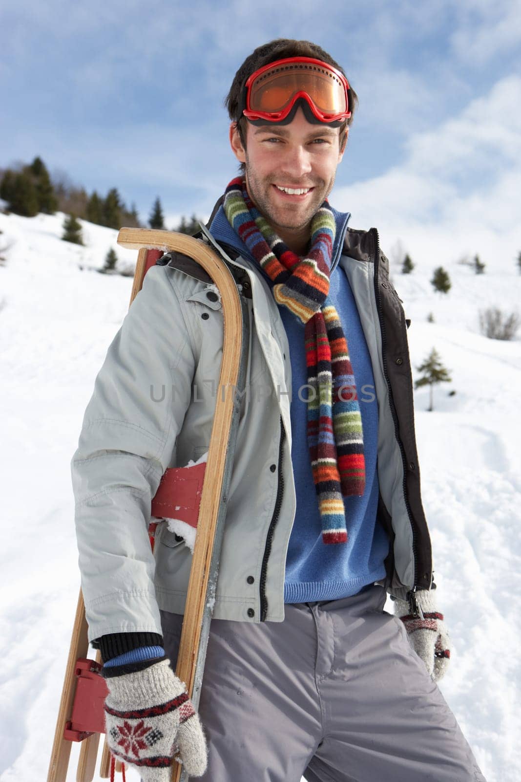 Young Man Carrying Sled In Alpine Landscape