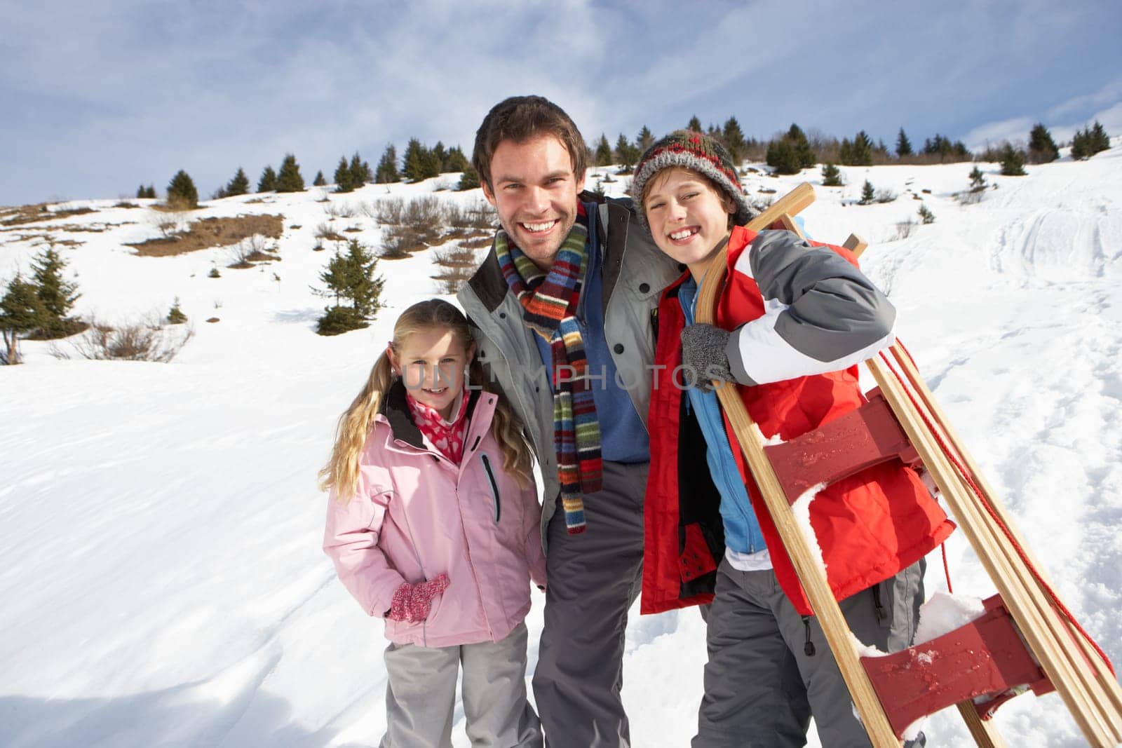 Young Father And Children In Snow With Sled