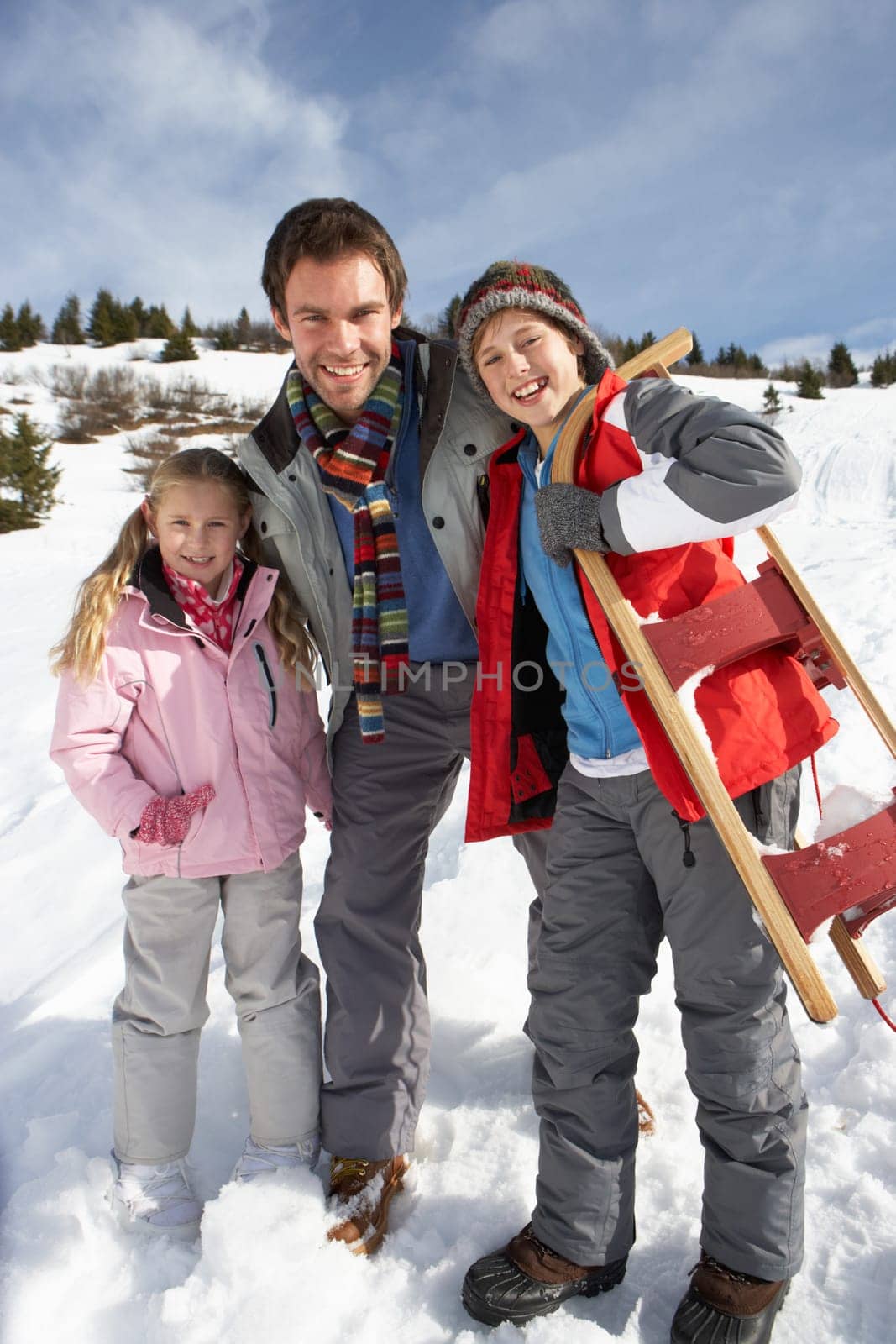 Young Father And Children In Snow With Sled