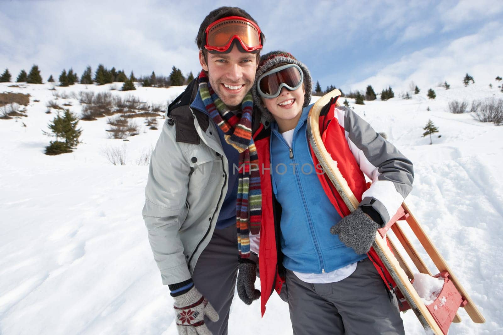Young Father And Son In Snow With Sled