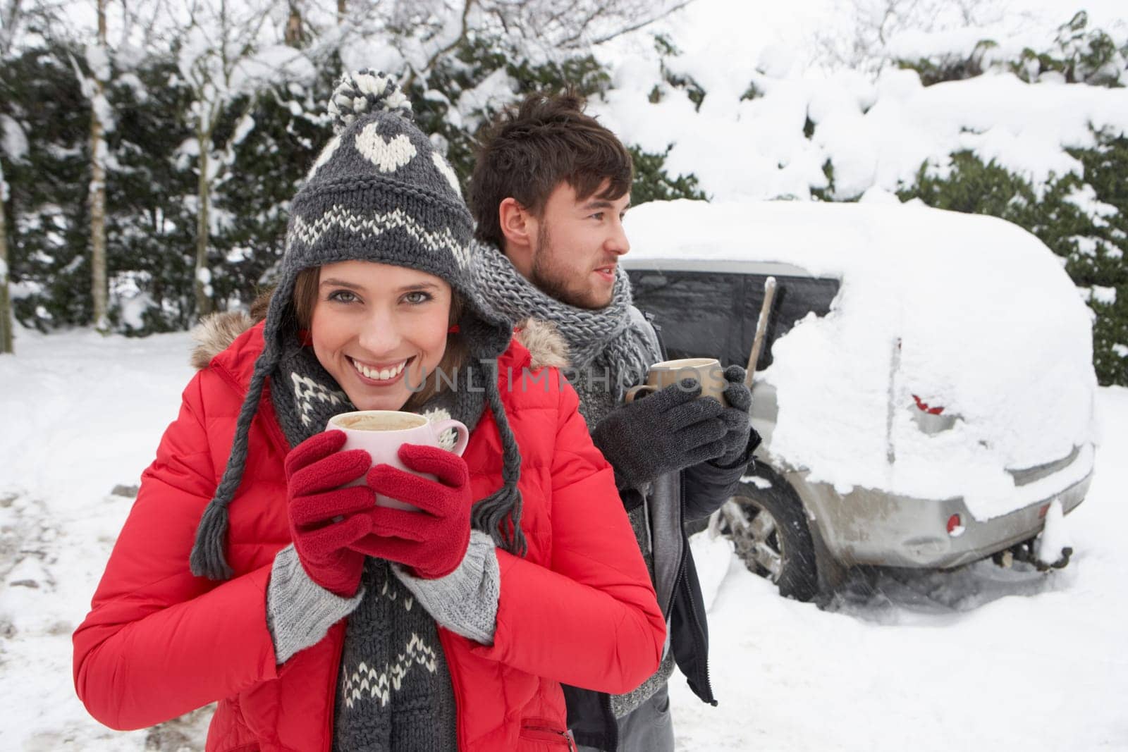 Young couple in snow with car