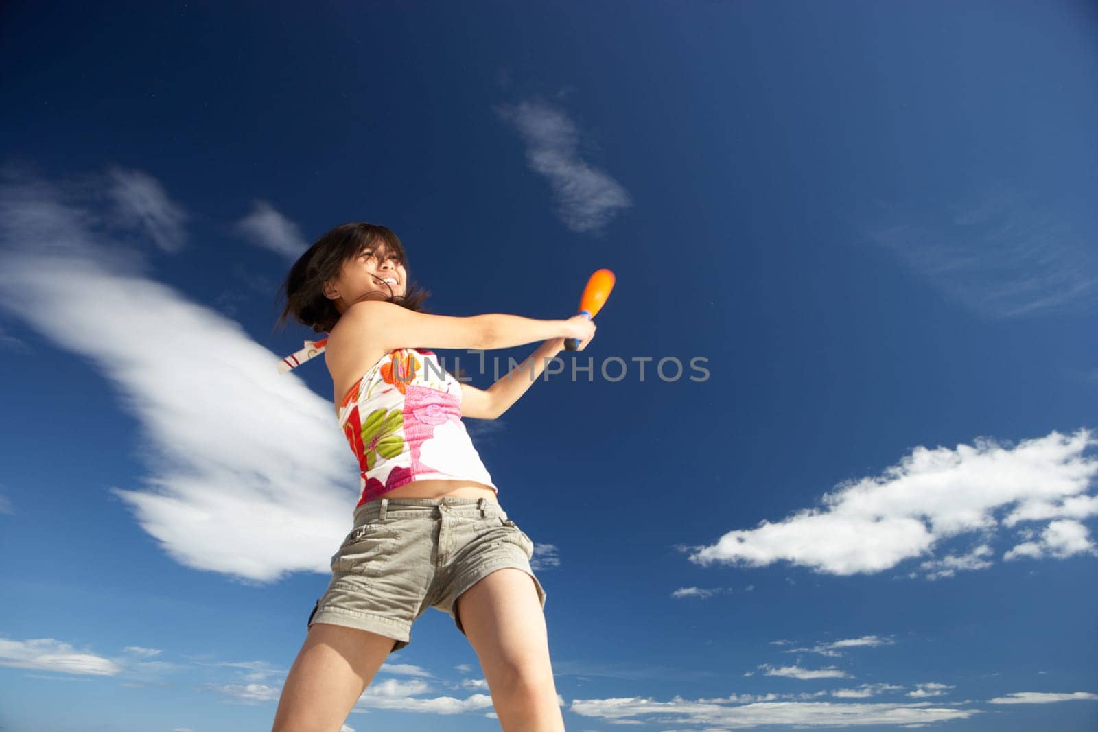 Teenage girl playing baseball on beach