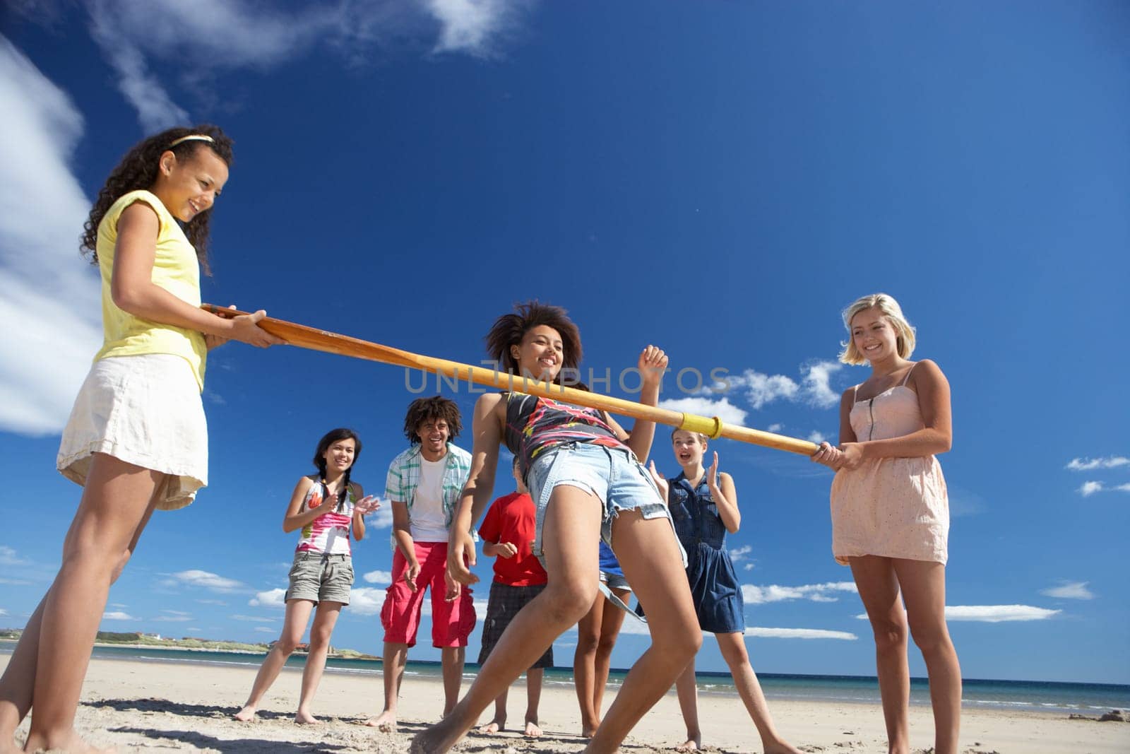 Teenagers doing limbo dance on beach