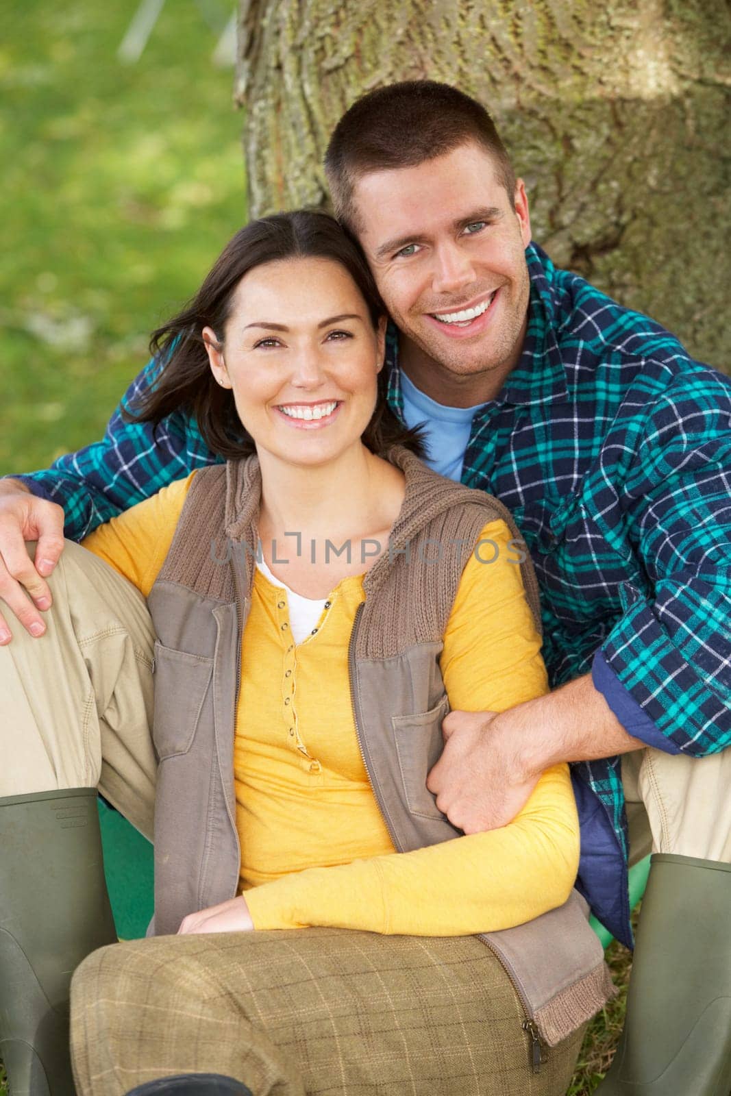 Couple sitting against tree trunk