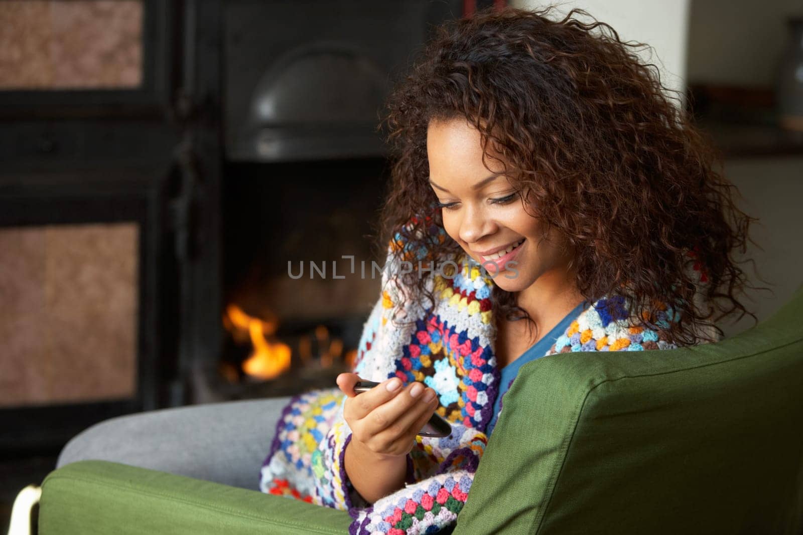 Young woman sitting by fire with phone