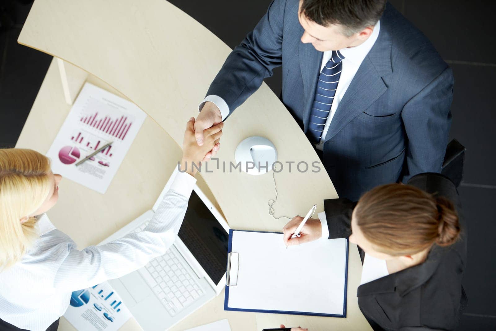 Image of business partners handshaking after signing contract