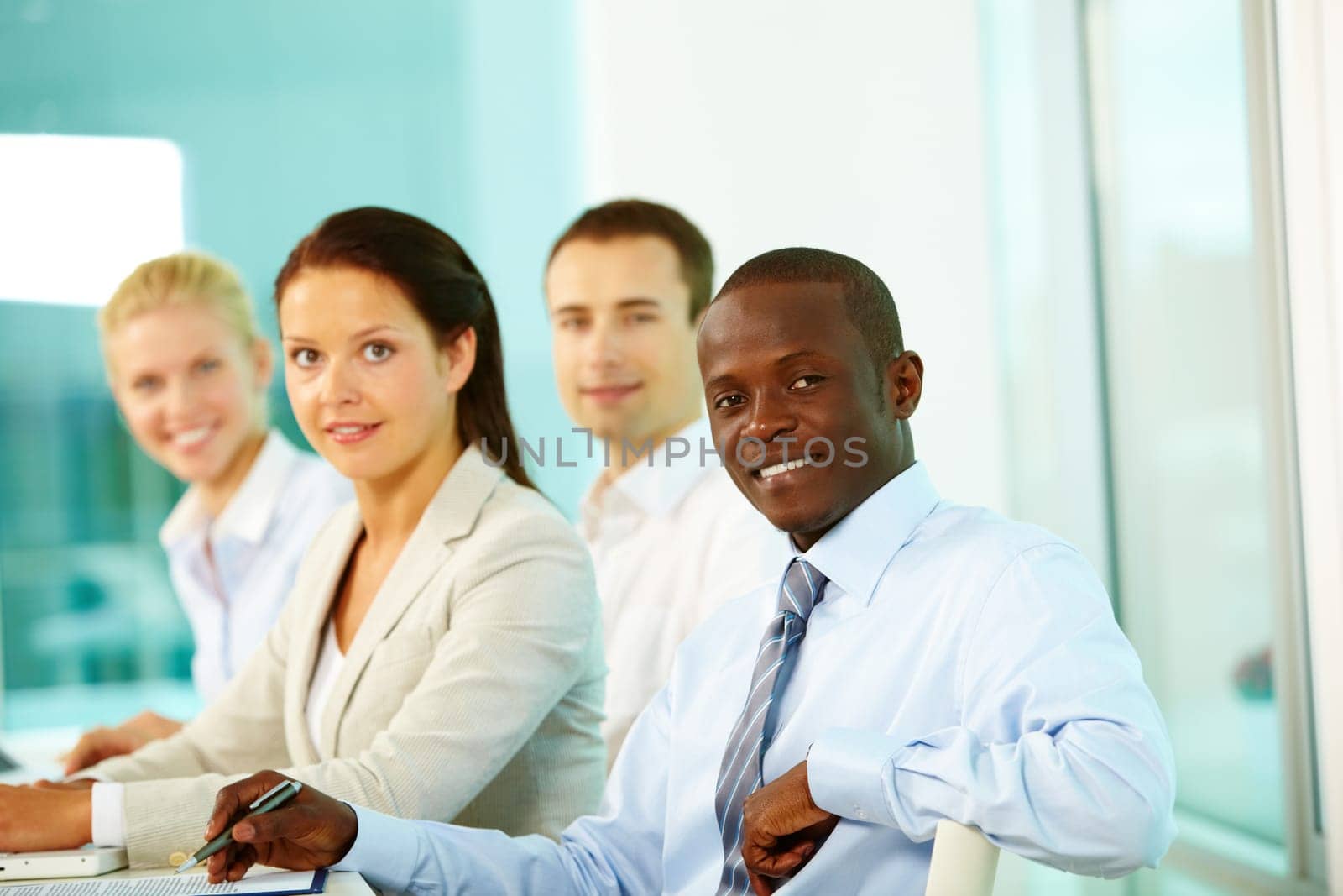 Four businesspeople in office looking at camera and smiling