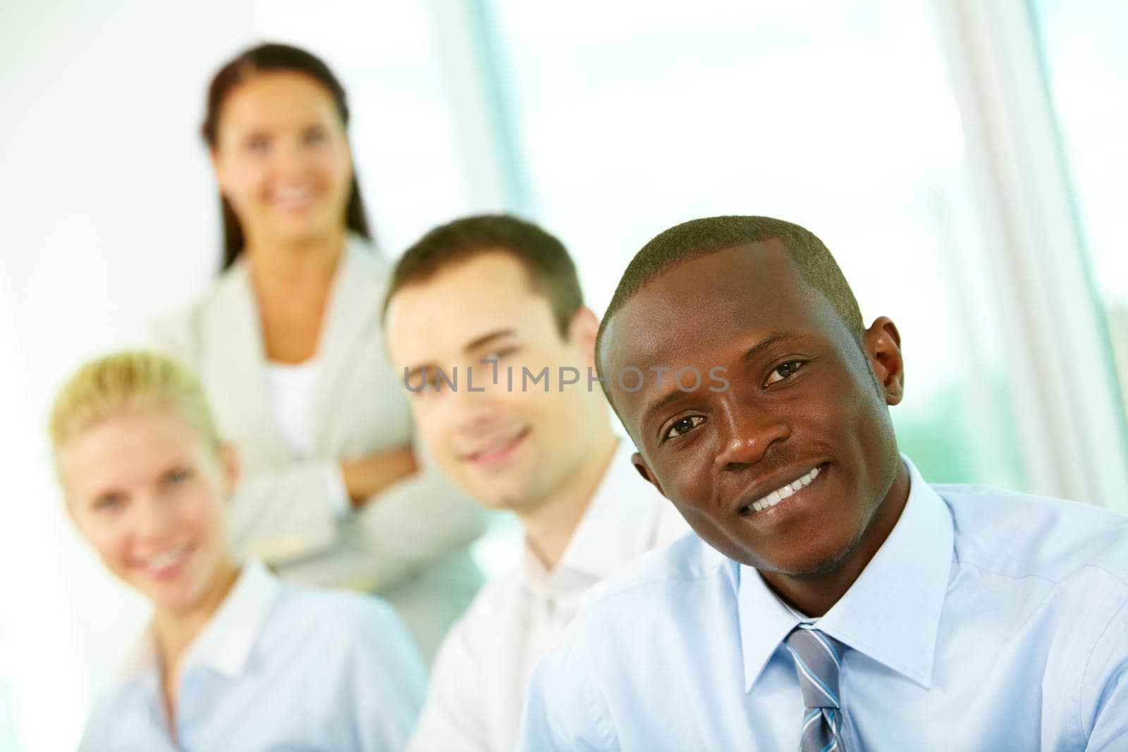 Four businesspeople looking at camera and smiling, the focus is on African American