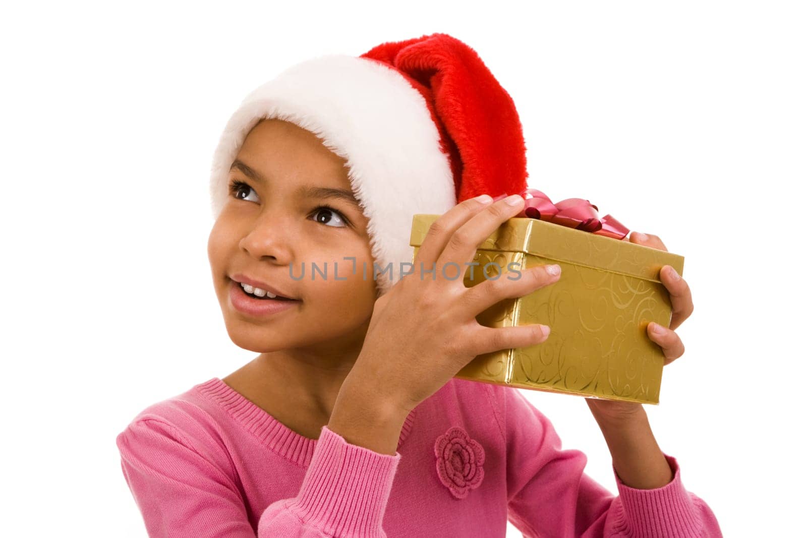 Curious girl in Santa cap listening to somewhat with giftbox by her ear