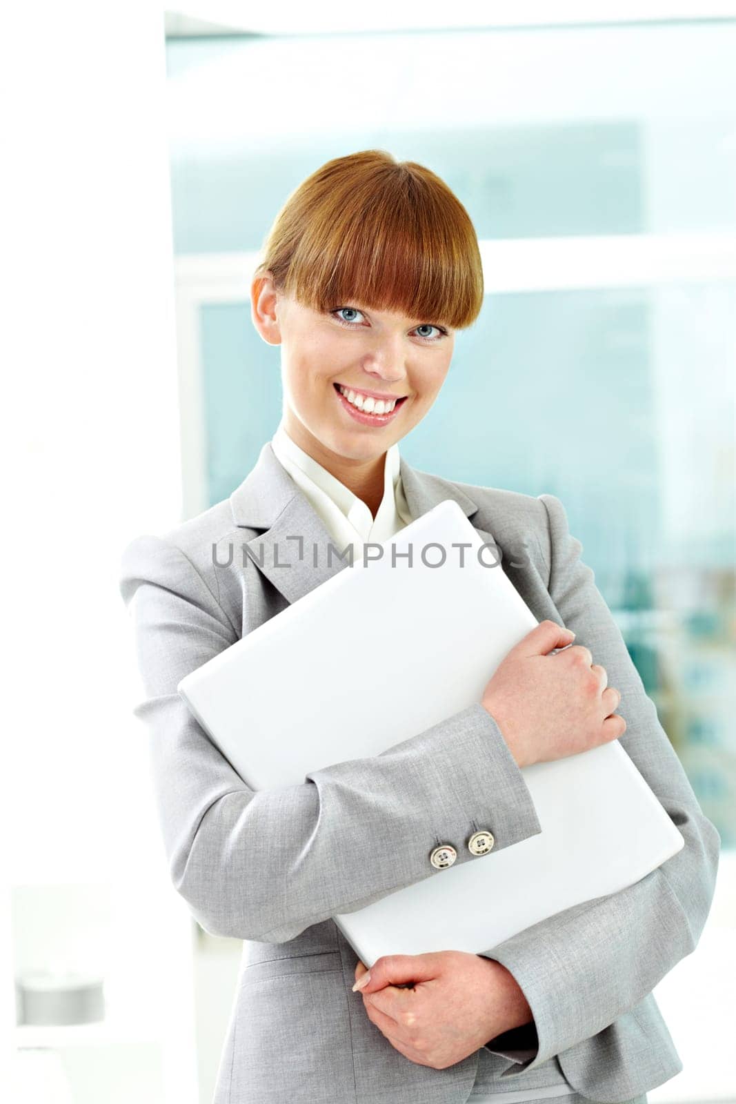 Portrait of cheerful girl holding laptop and looking at camera