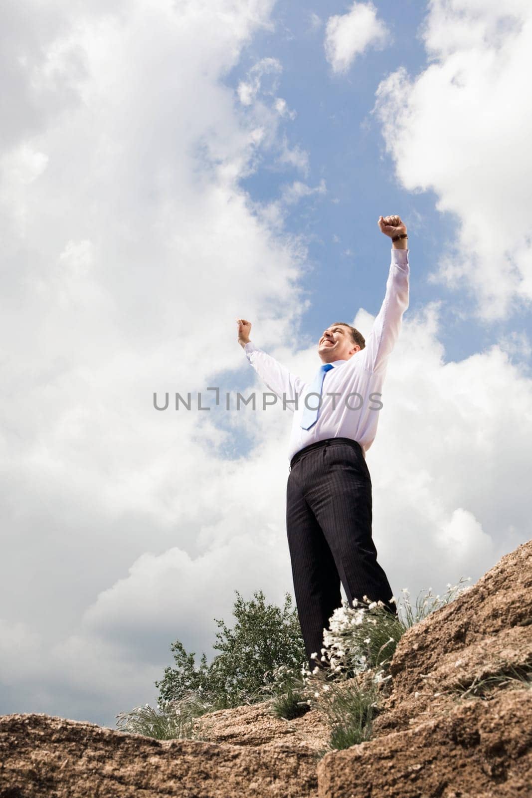 Photo of relaxed businessman standing and raising his arms outdoors in summer