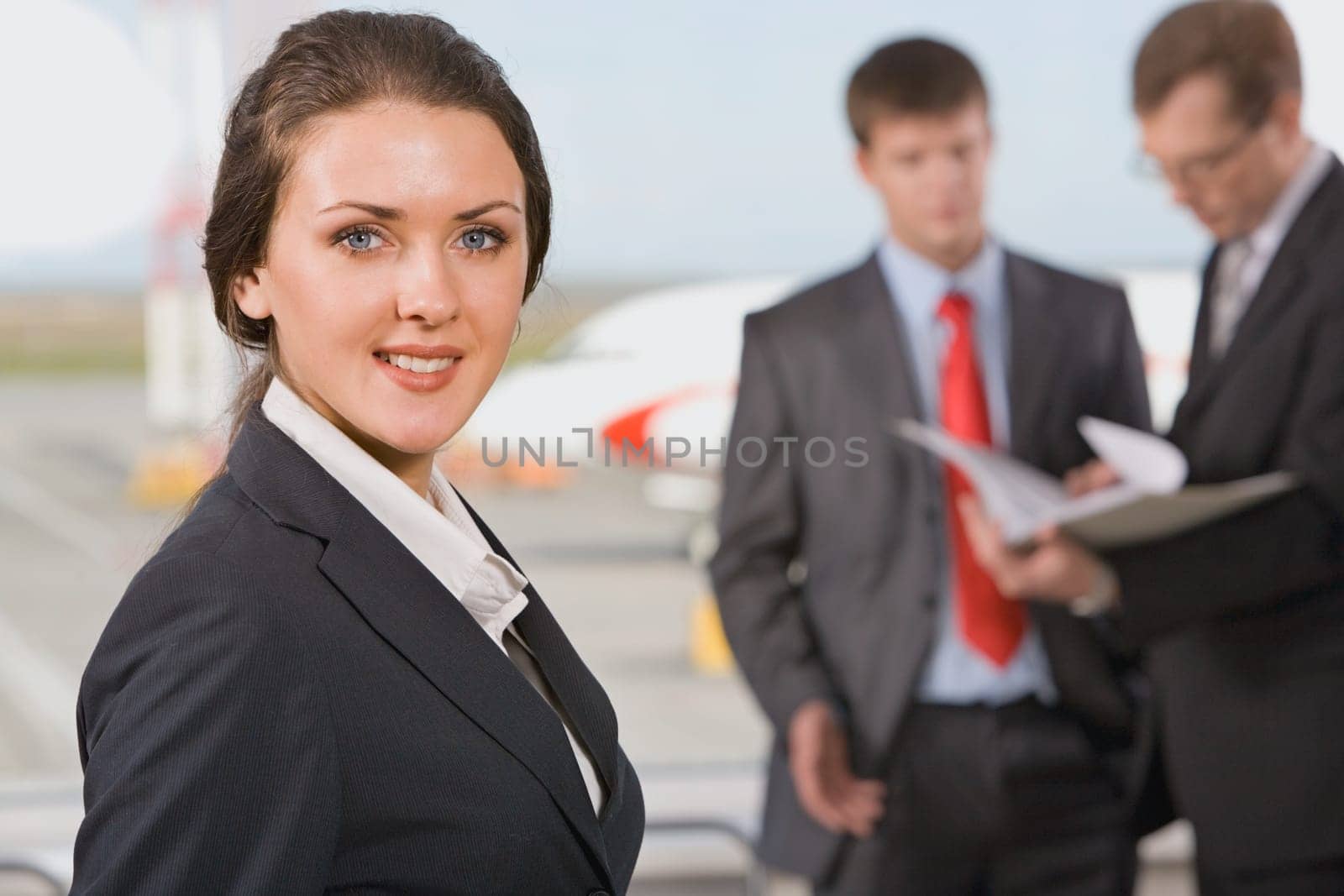 Portrait of successful woman smiling on the background of two  business people in an airport