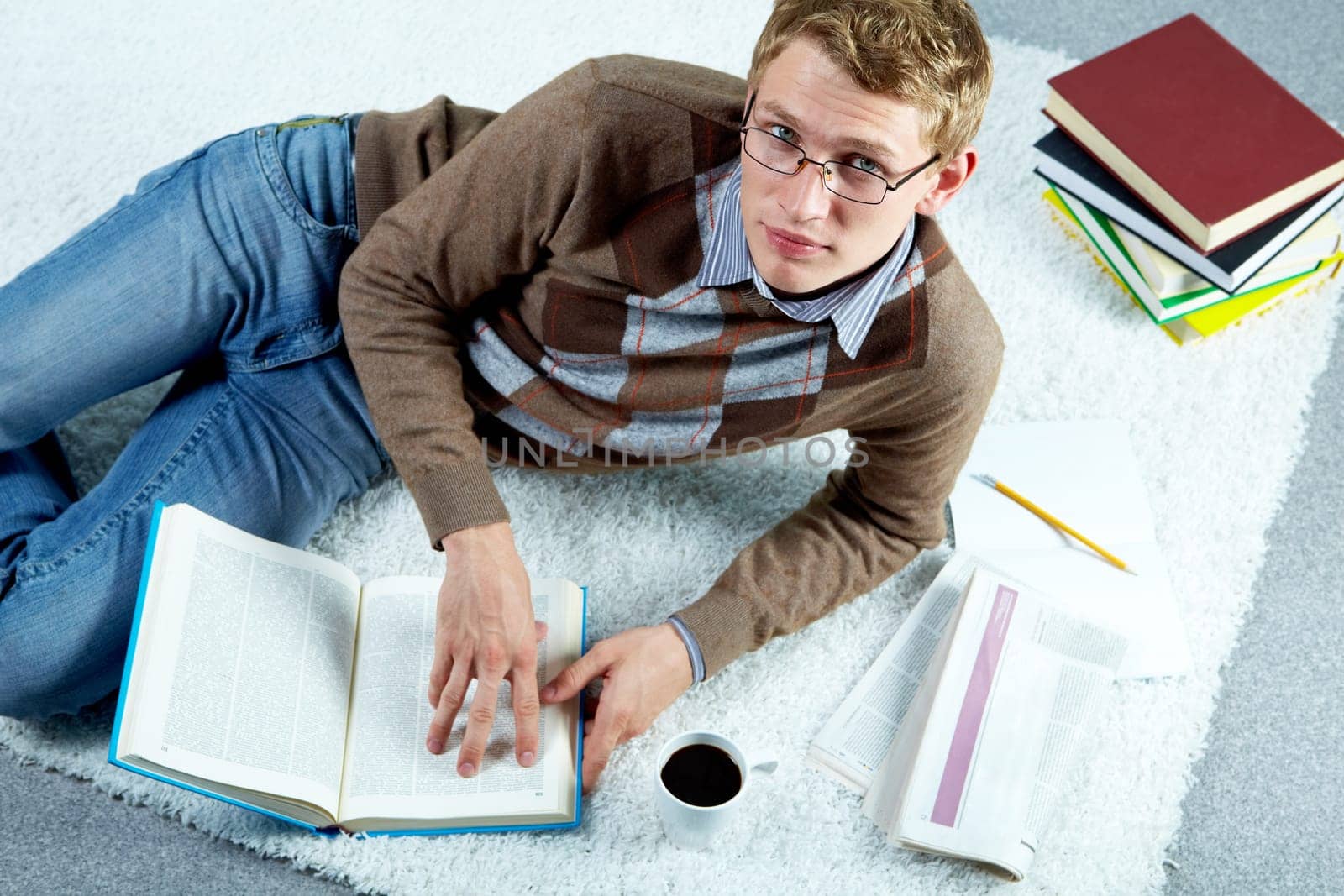 Image of serious student lying on the floor and reading book