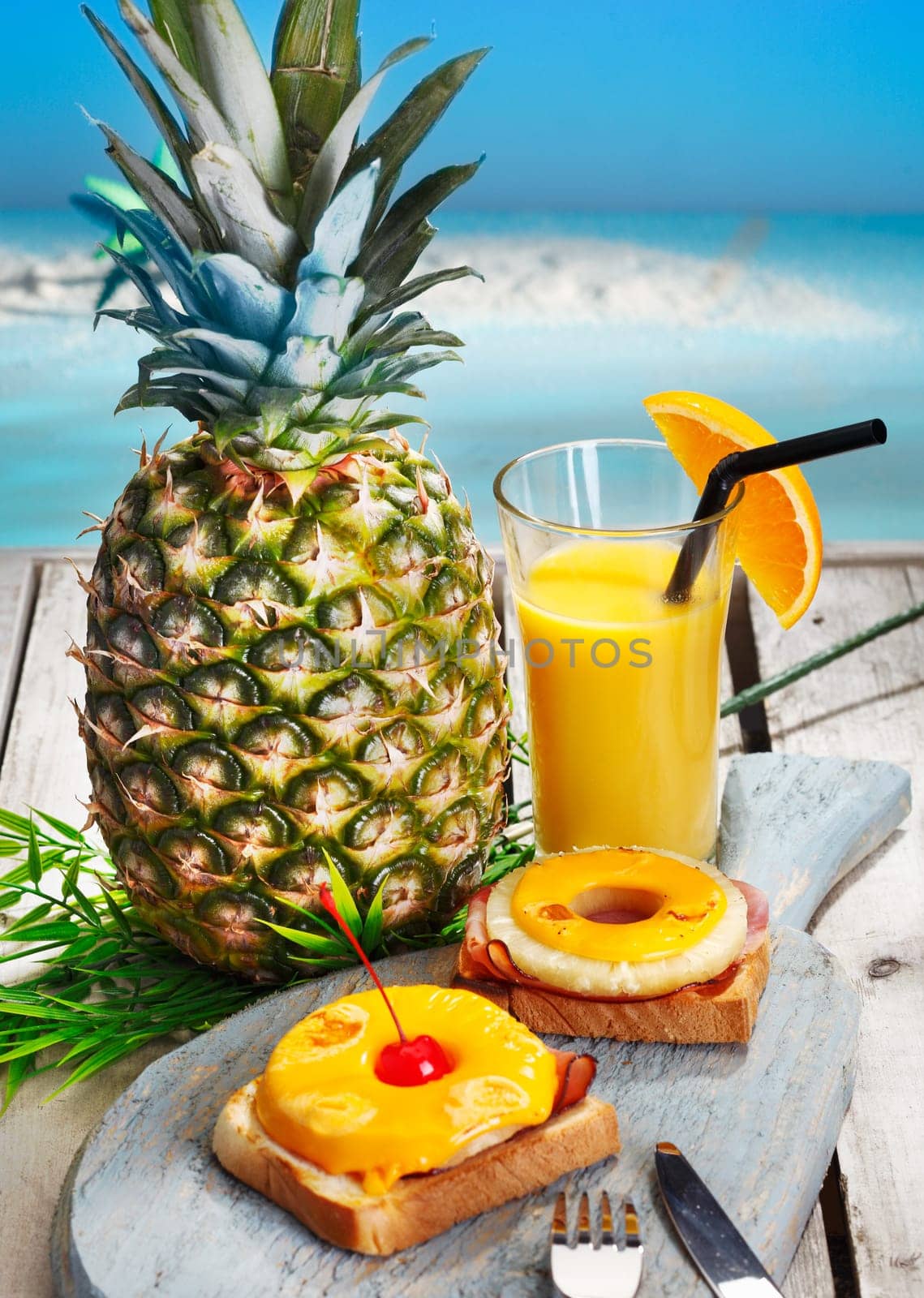 Pineapple rings with melted cheese on ham served on toast with freshly sqeezed orange juice for a healthy tropical breakfast or lunch