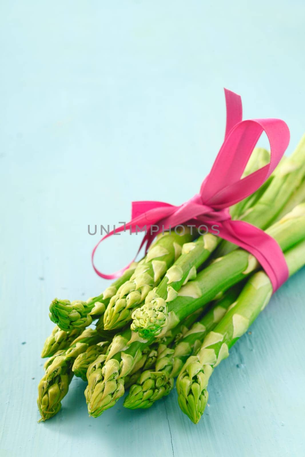 Bunch of fresh young asparagus tips tied with a decorative pink ribbon