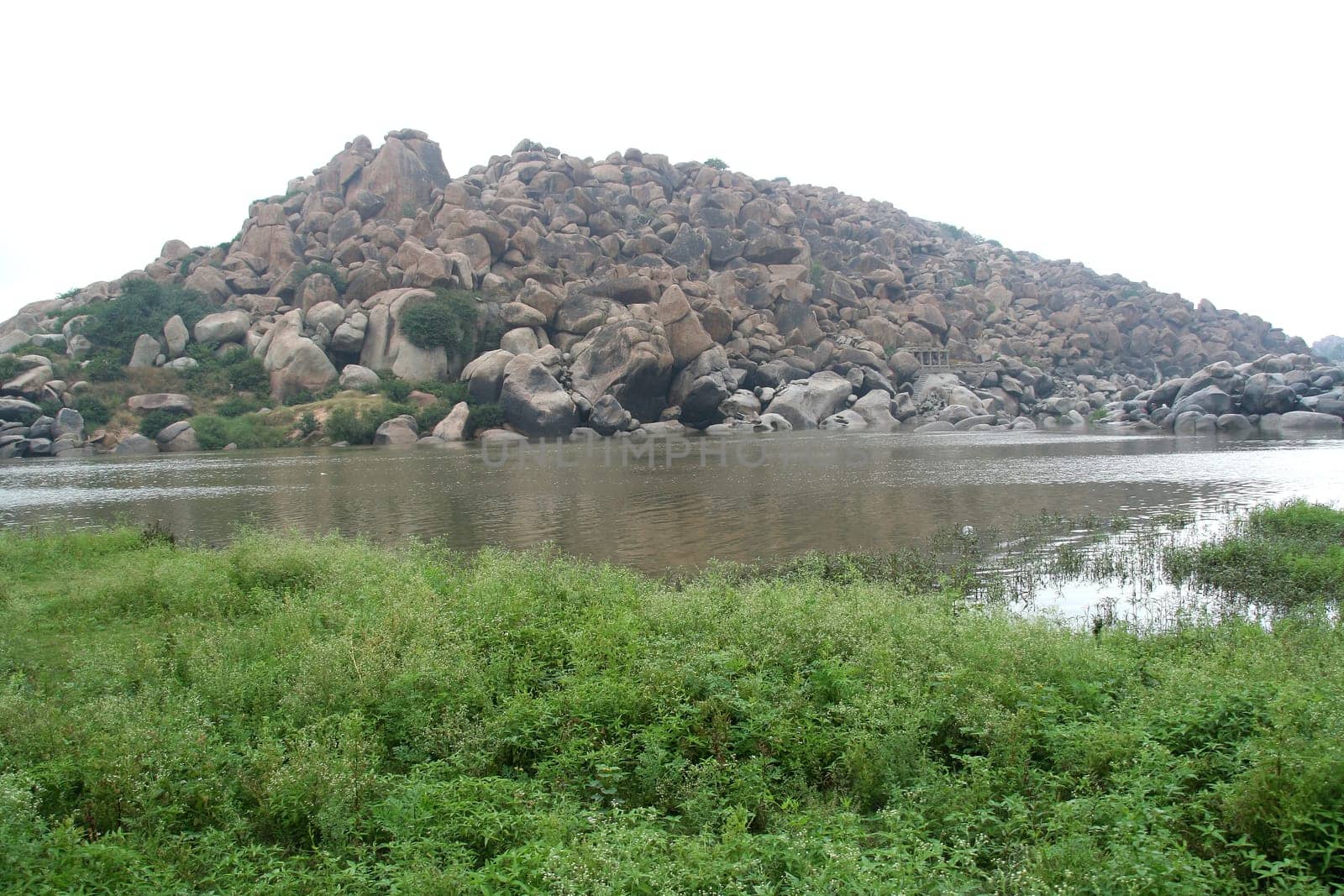View of Tungabhadra River and rocky hill with grass foreground at Hampi, Karnataka, India, Asia