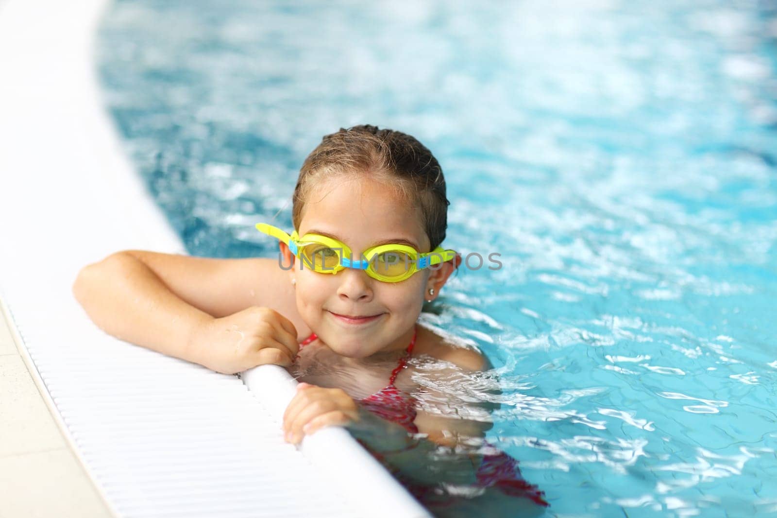 Cute girl with goggles in swimming pool