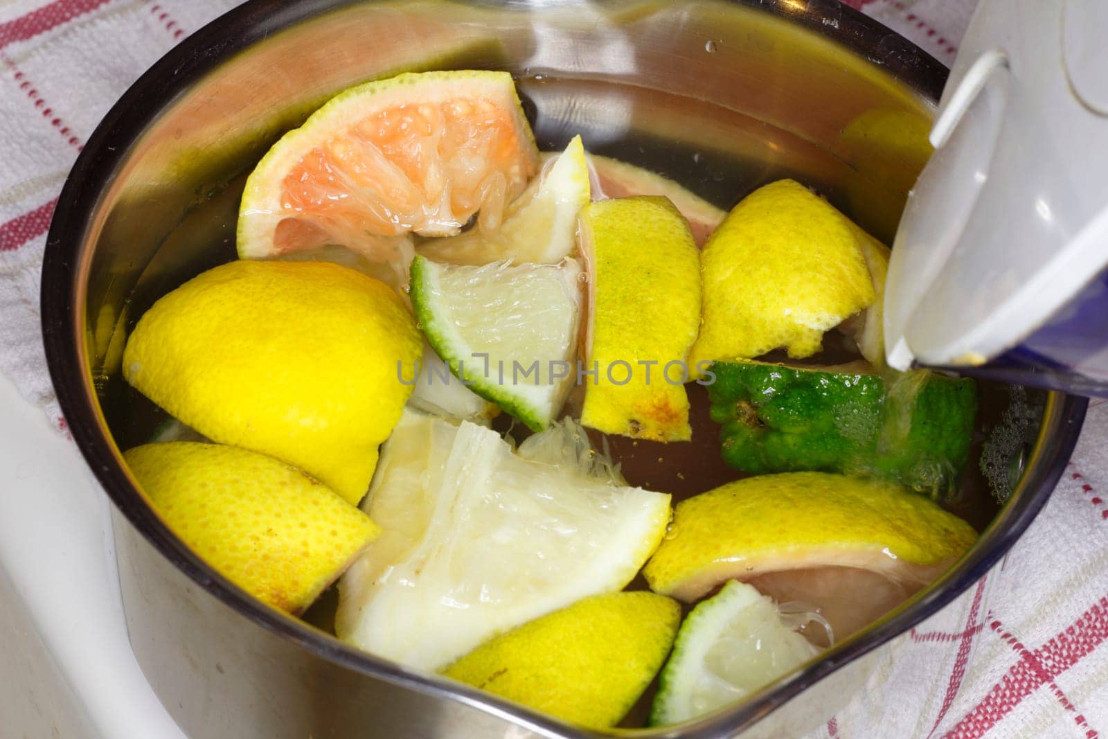 Water being poured in a pan of cut up citrus fruits to heat it up on the stove for some relaxing aromatherapy.