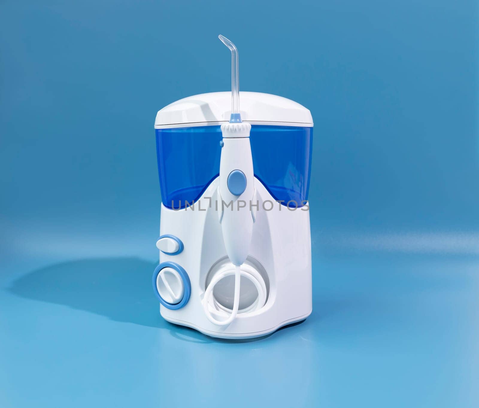 Water Flosser, Dental Oral Irrigator On Blue Background. Dental Equipment Care. Irrigator For Mouth. Cleaning Teeth With Water Jet Under Pressures. Horizontal Plane. by netatsi