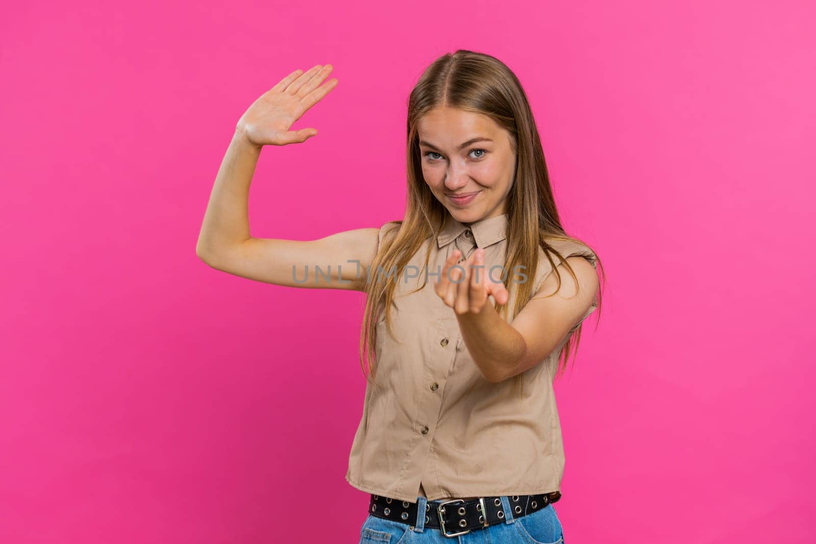 Come here, join us. Welcome. Blonde attractive woman showing inviting gesture with hands, ask to join, beckoning to coming, gesturing hello, goodbye. Pretty girl isolated on pink studio background