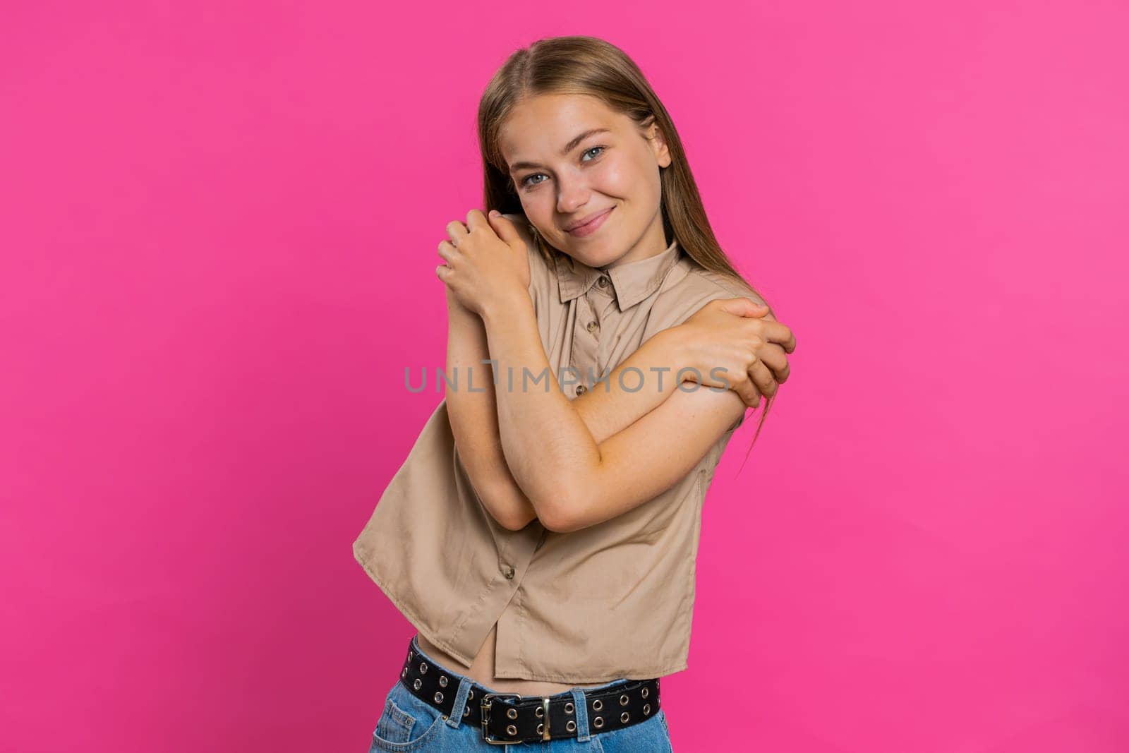 Come to me, I want to embrace you. Young woman spread hands and give hug to you. Pleasant expression, love feelings, proud, satisfied. Girl isolated alone on pink studio background. Lifestyles