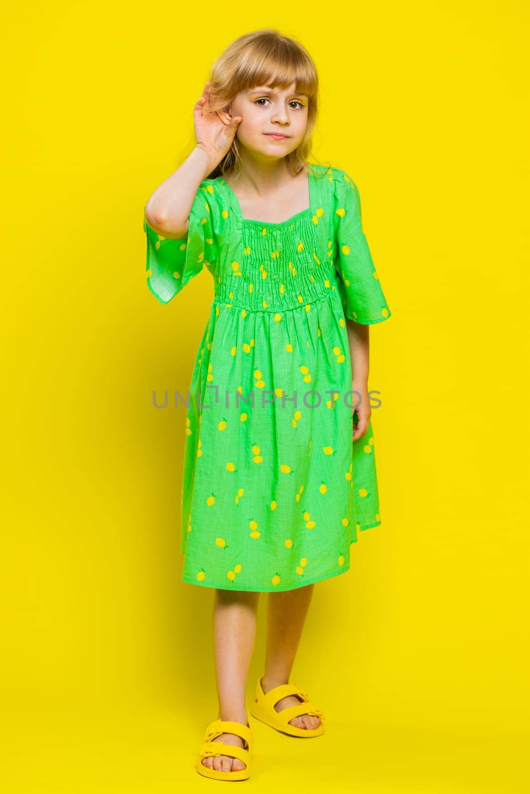 I cant hear you. What. Child girl kid trying hear you, looking confused, frowning, keeping arm near ear for louder voice, asking to repeat, to hear information, deafness. Preteen children. Vertical