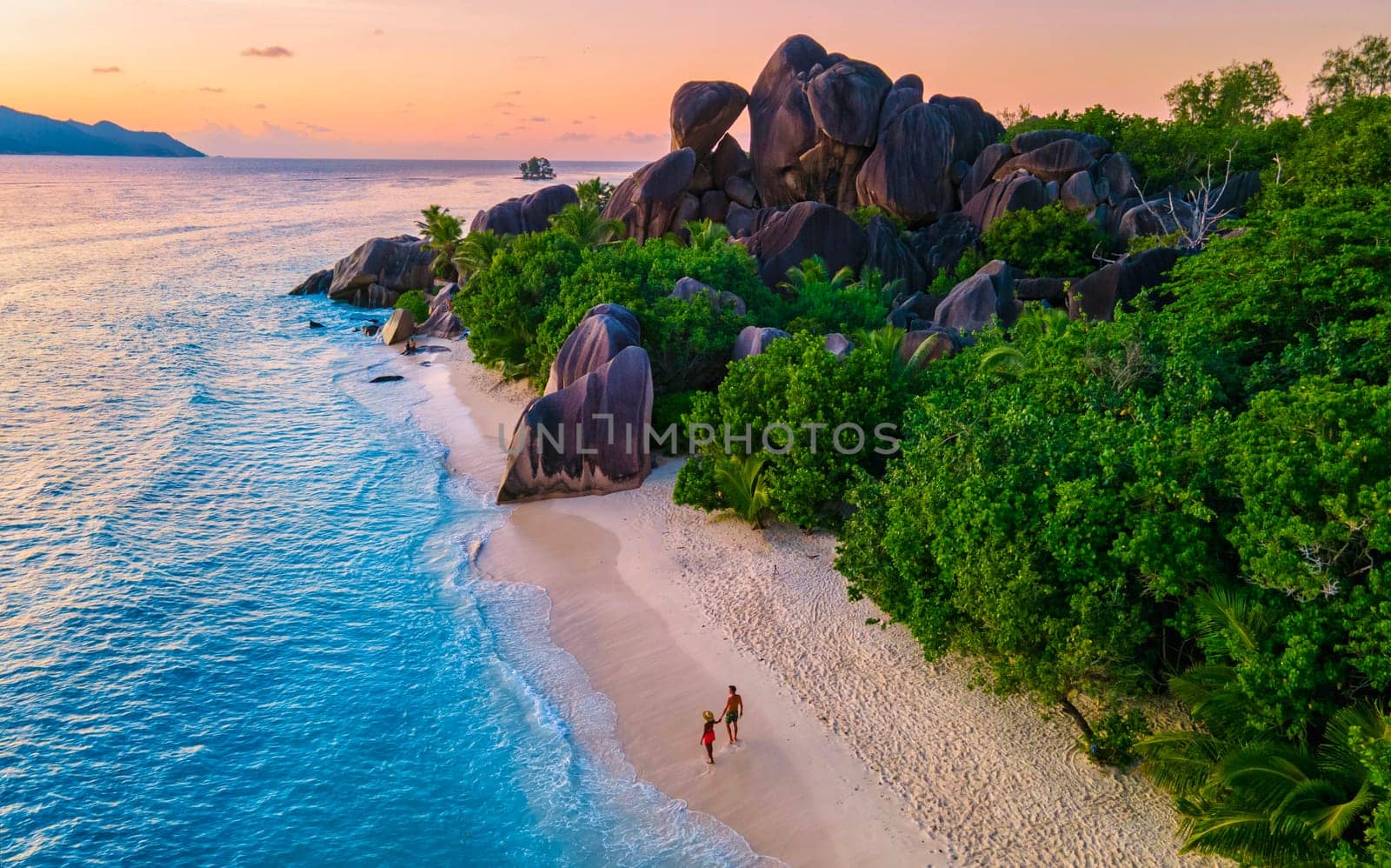 Anse Source d'Argent beach, La Digue Island, Seychelles, aerial view of La Digue Seychelles a tropical Island, couple men and woman walking at the beach during sunset at a luxury vacation