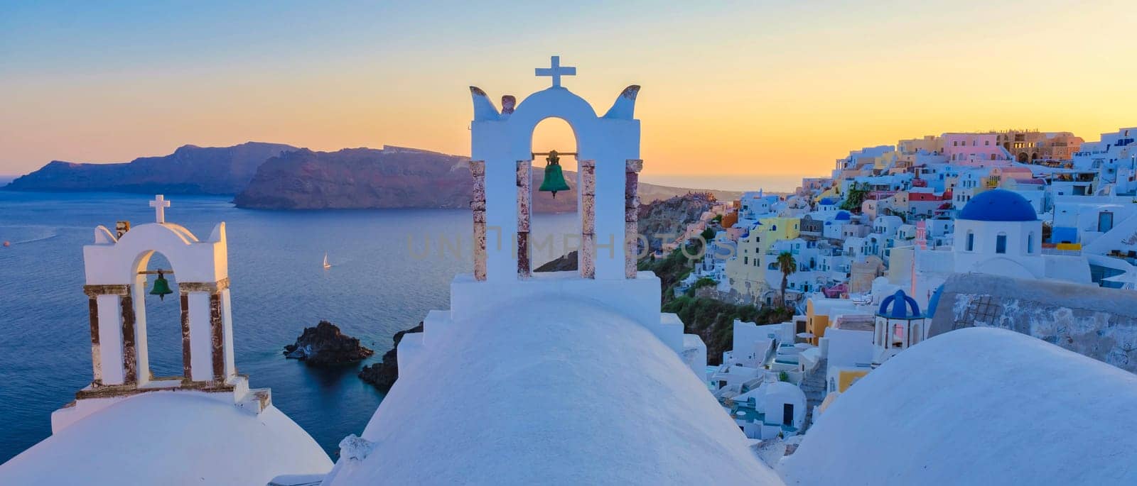 Oia Santorini Greece, a traditional Greek village in Santorini with whitewashed churches and blue domes at sunset