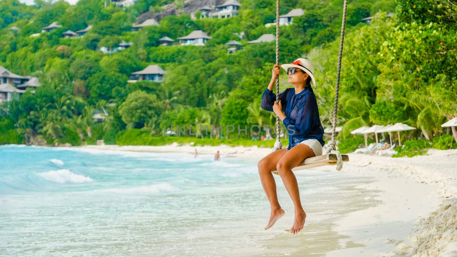 Young women at a swing on a tropical beach in Mahe Tropical Seychelles Islands. woman looking out over the ocean from a swing at the beach in the Seychelles