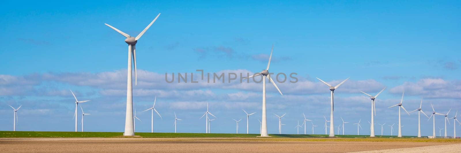 Windmill park on the dike of Lake Ijsselmeer, drone aerial view of windmill turbines generating green energy, windmills in the Netherlands.