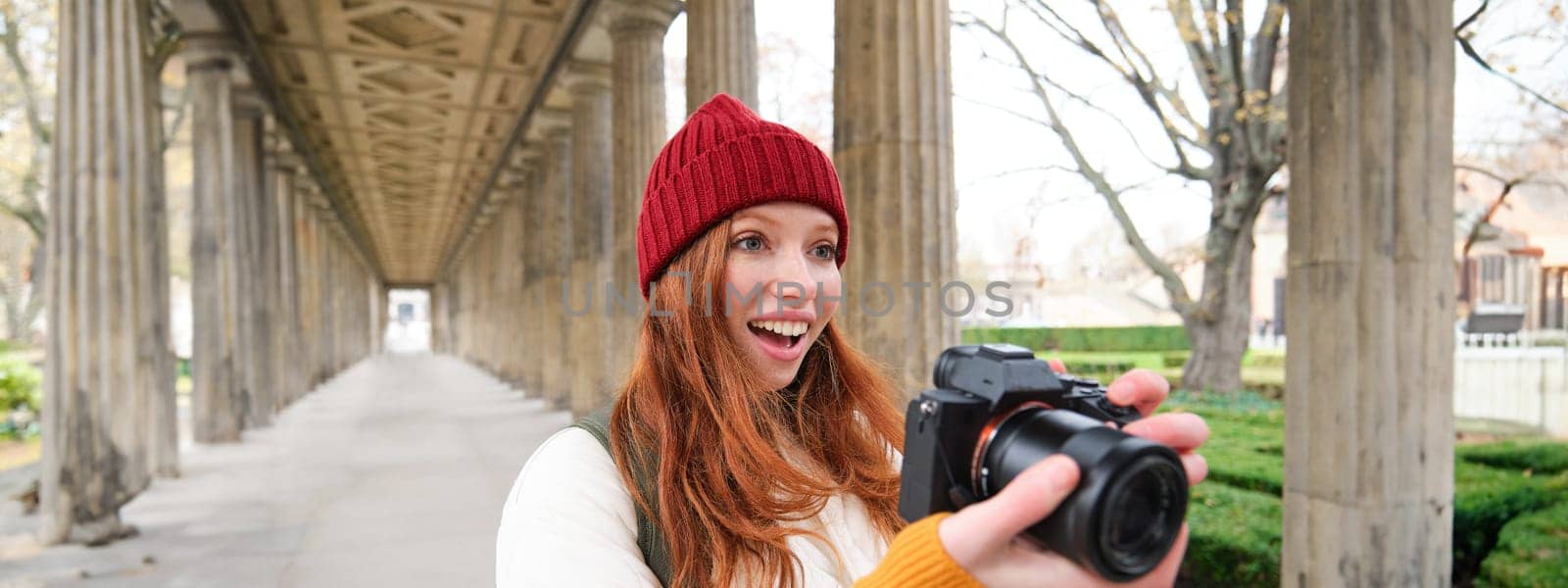 Smiling tourist photographer, takes picture during her trip, holds professional camera and makes photos. Copy space