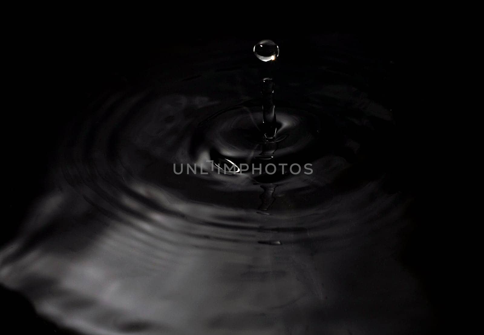 A water drop fall in water, on black background