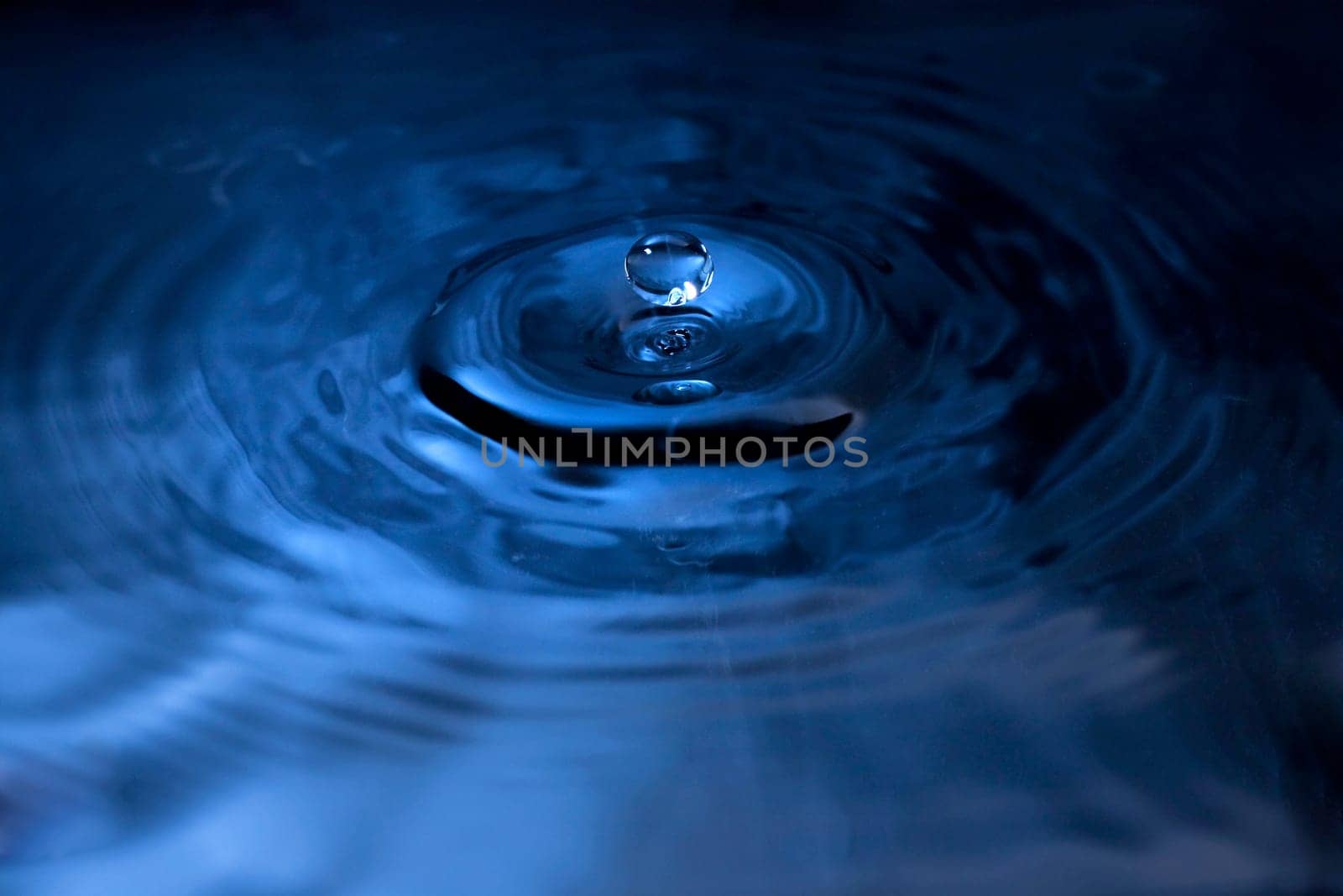 A water drop fall in water, photographed with blue filter