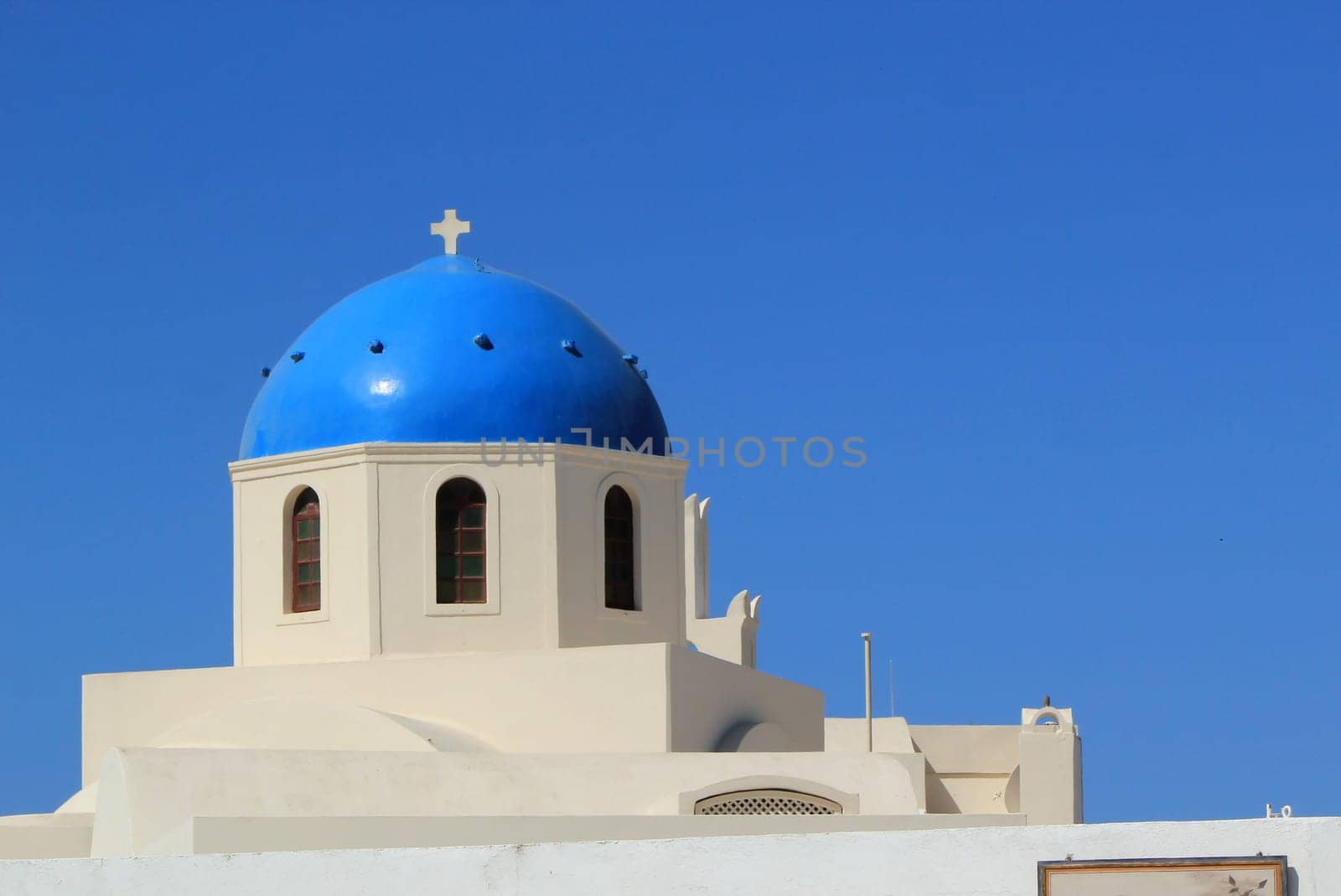 Close up of the blue dome and small cross of a typical orthodox church at Oia by beautiful weather, Santorini, Greece