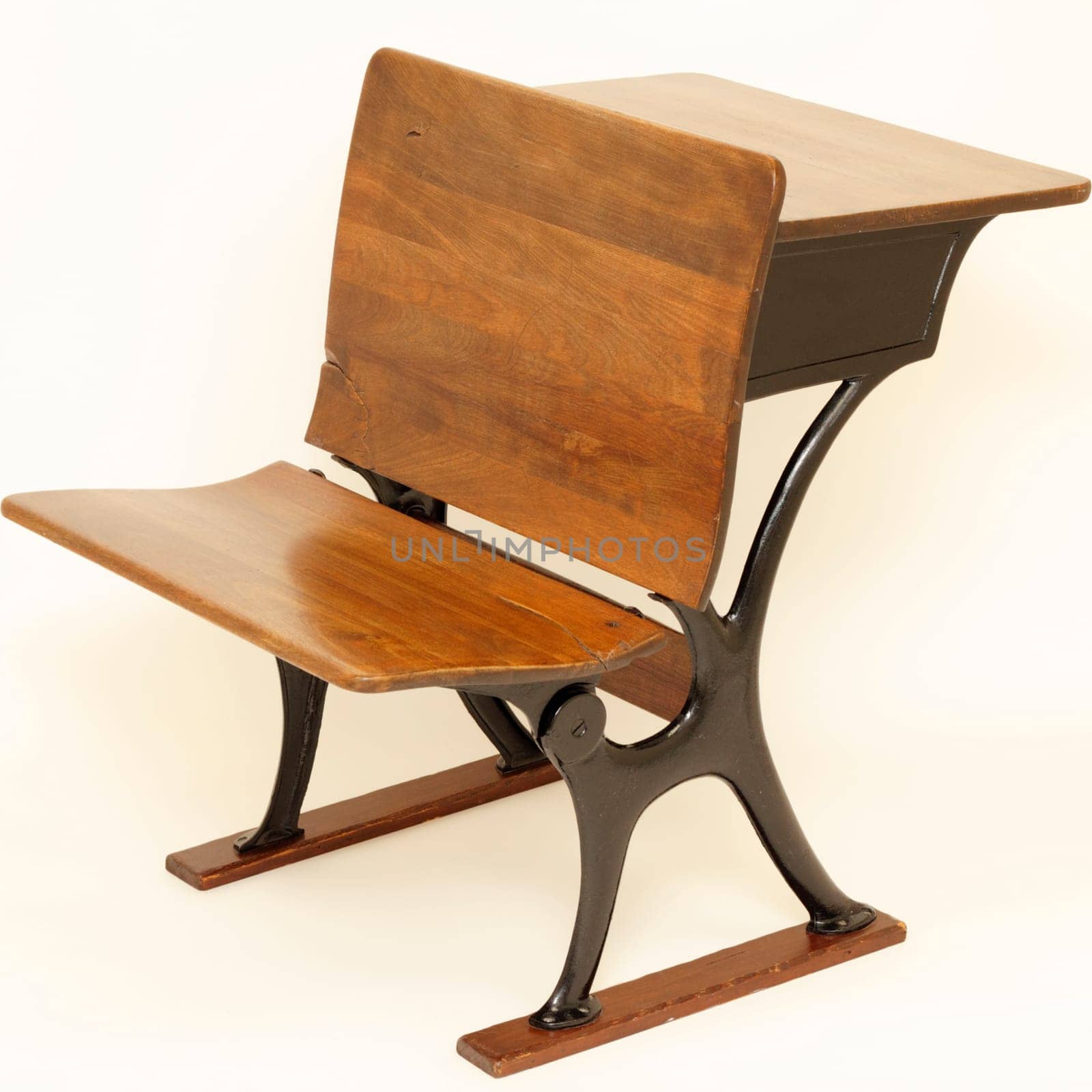 Old wood and metal combination school chair in front and school desk in back.