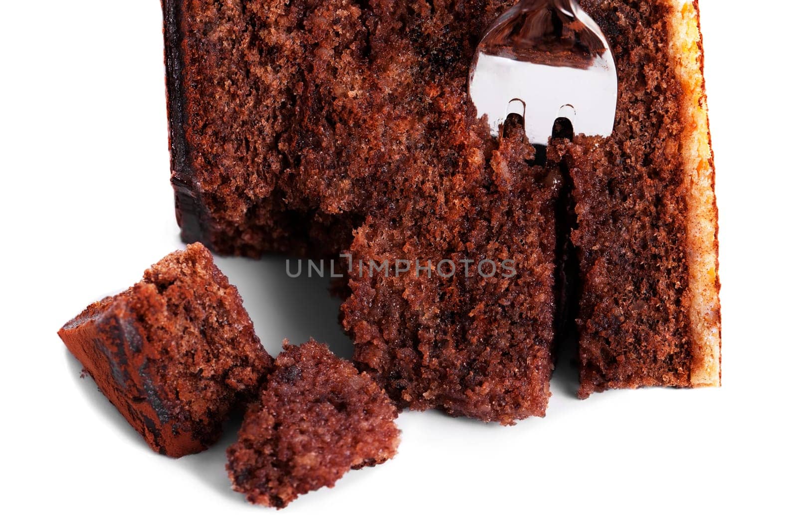 Broken chocolate cake with fork on white background