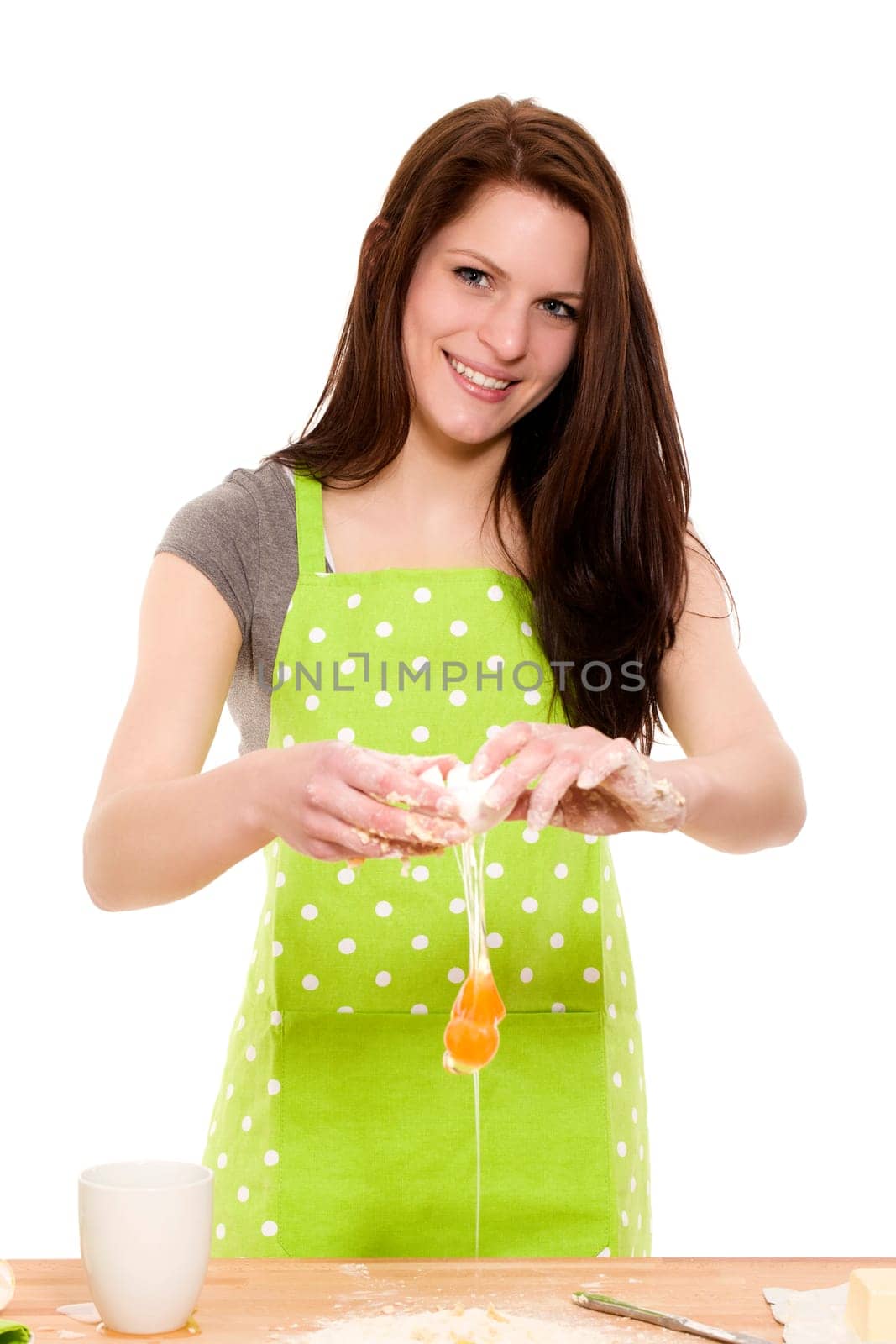 Young woman cracking egg against white background