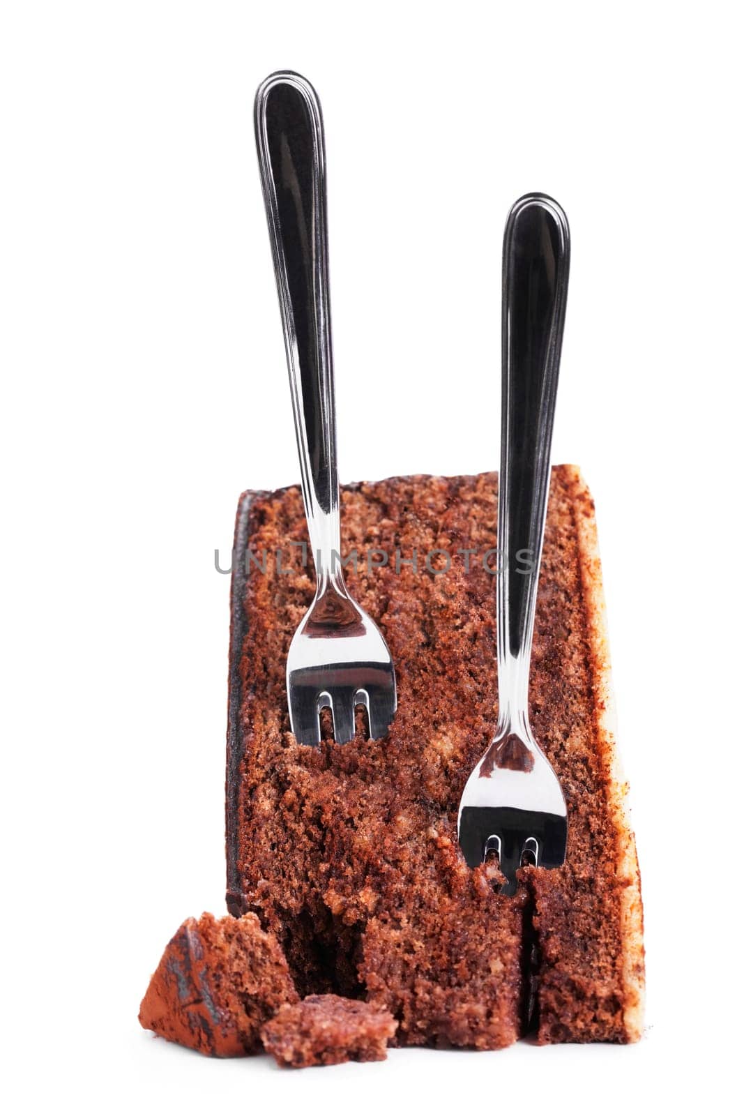 Two cake forks in broken chocolate cake on white background