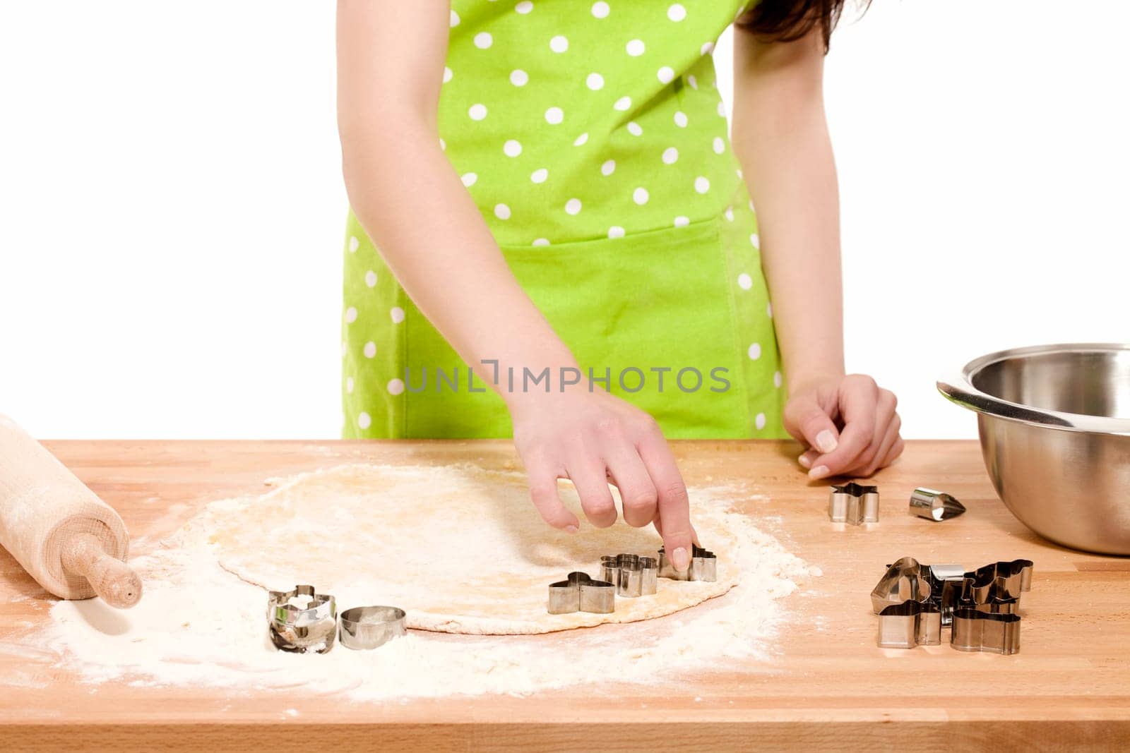 Woman pressing Christmas cookie cutter in dough against white background