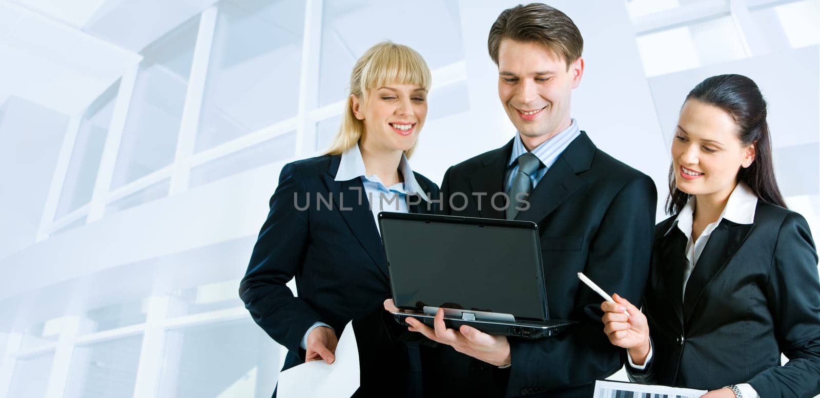 Successful businesspeople looking at the laptop screen on the background of office building