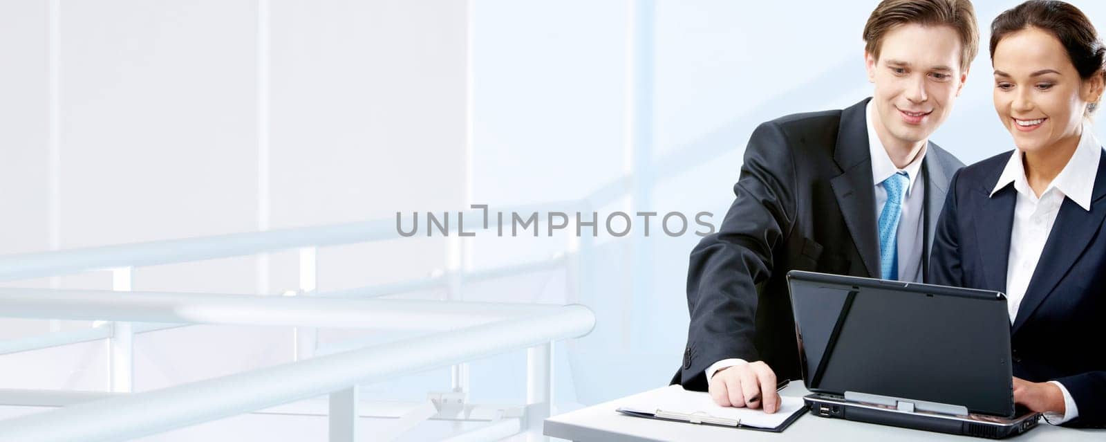 Image of two working people looking at laptop screen in office